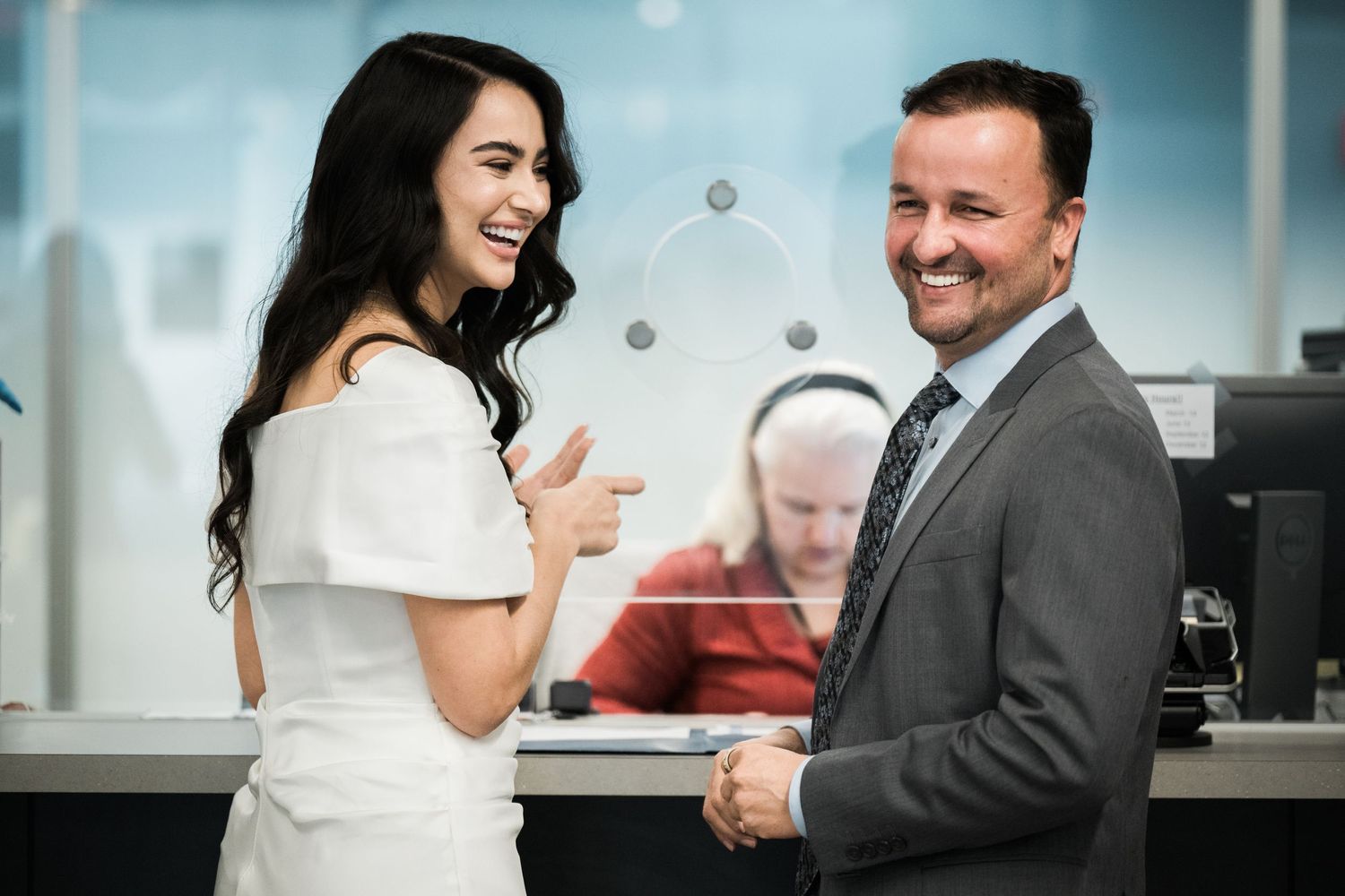 A couple shares a joyful moment in an office setting with decorative floral arrangements.