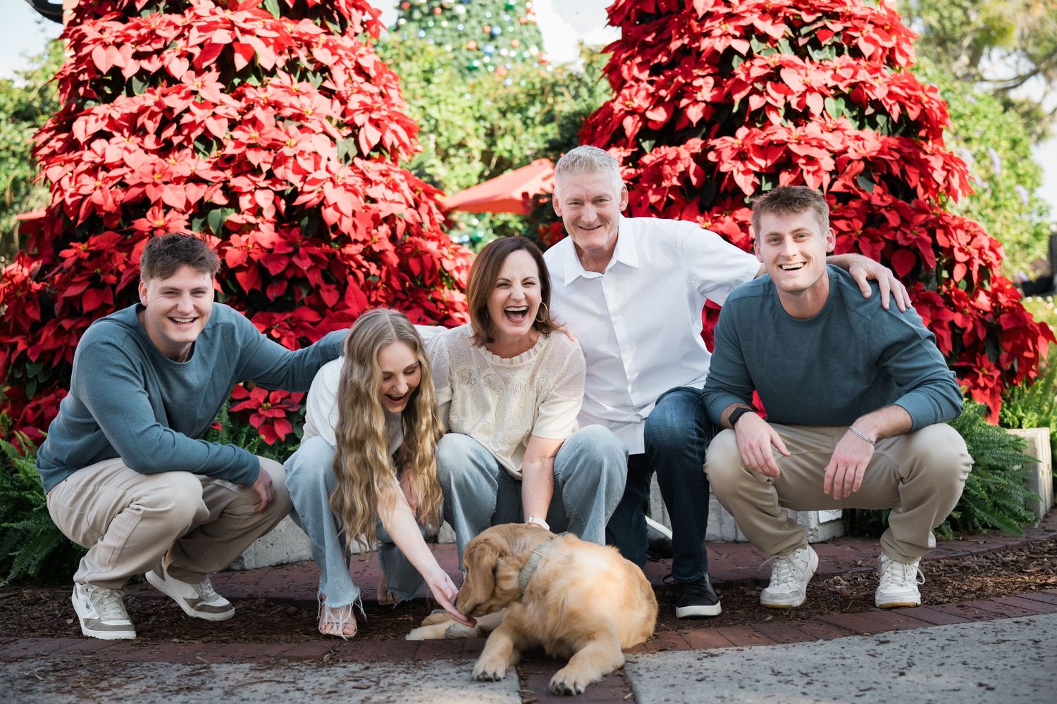 A group poses playfully in front of vibrant red foliage during an outdoor photo session.