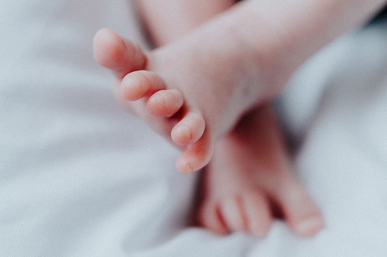 Close-up of delicate baby toes against soft white bedding.