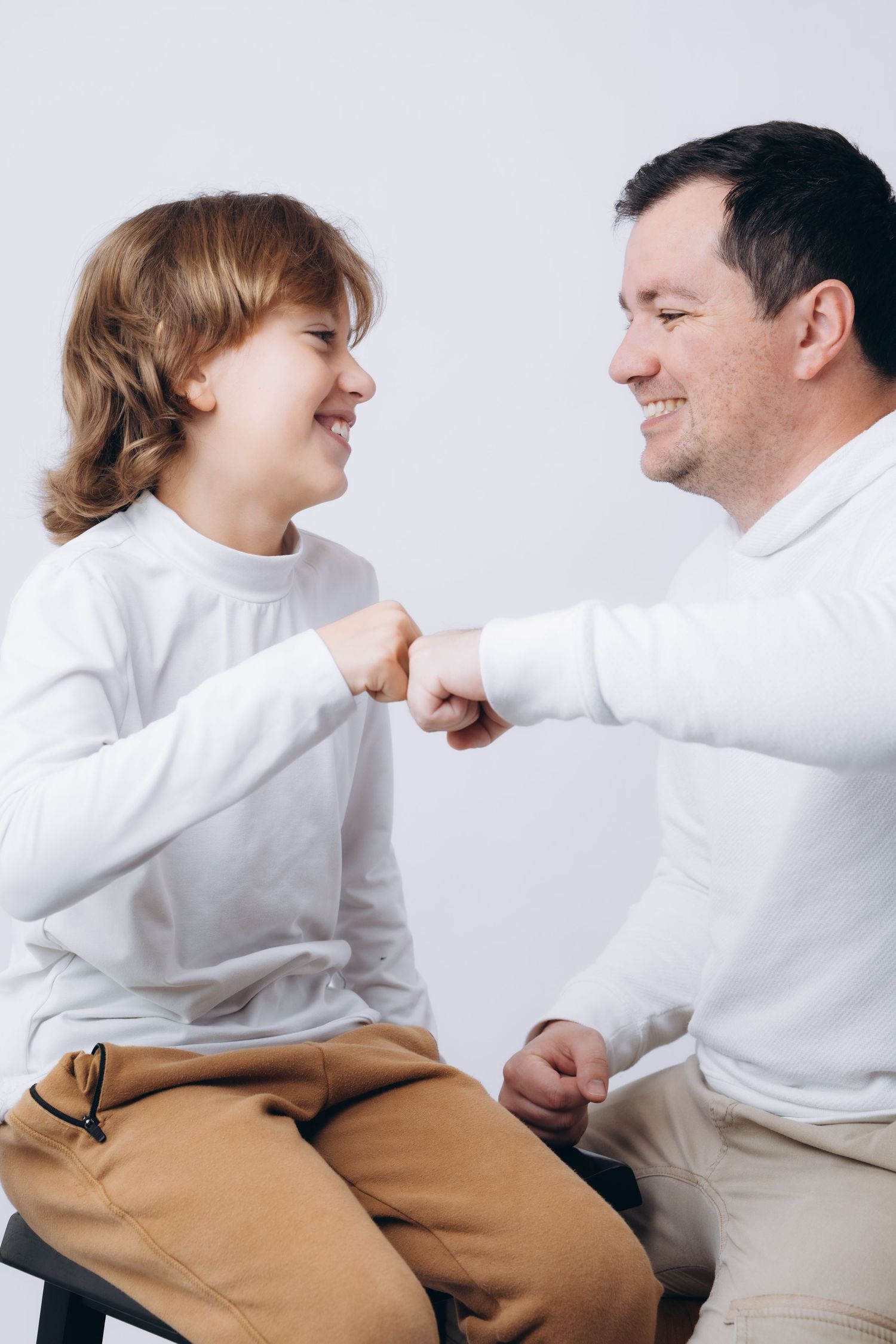 Two people in white shirts fist bump while sharing genuine smiles and laughter.