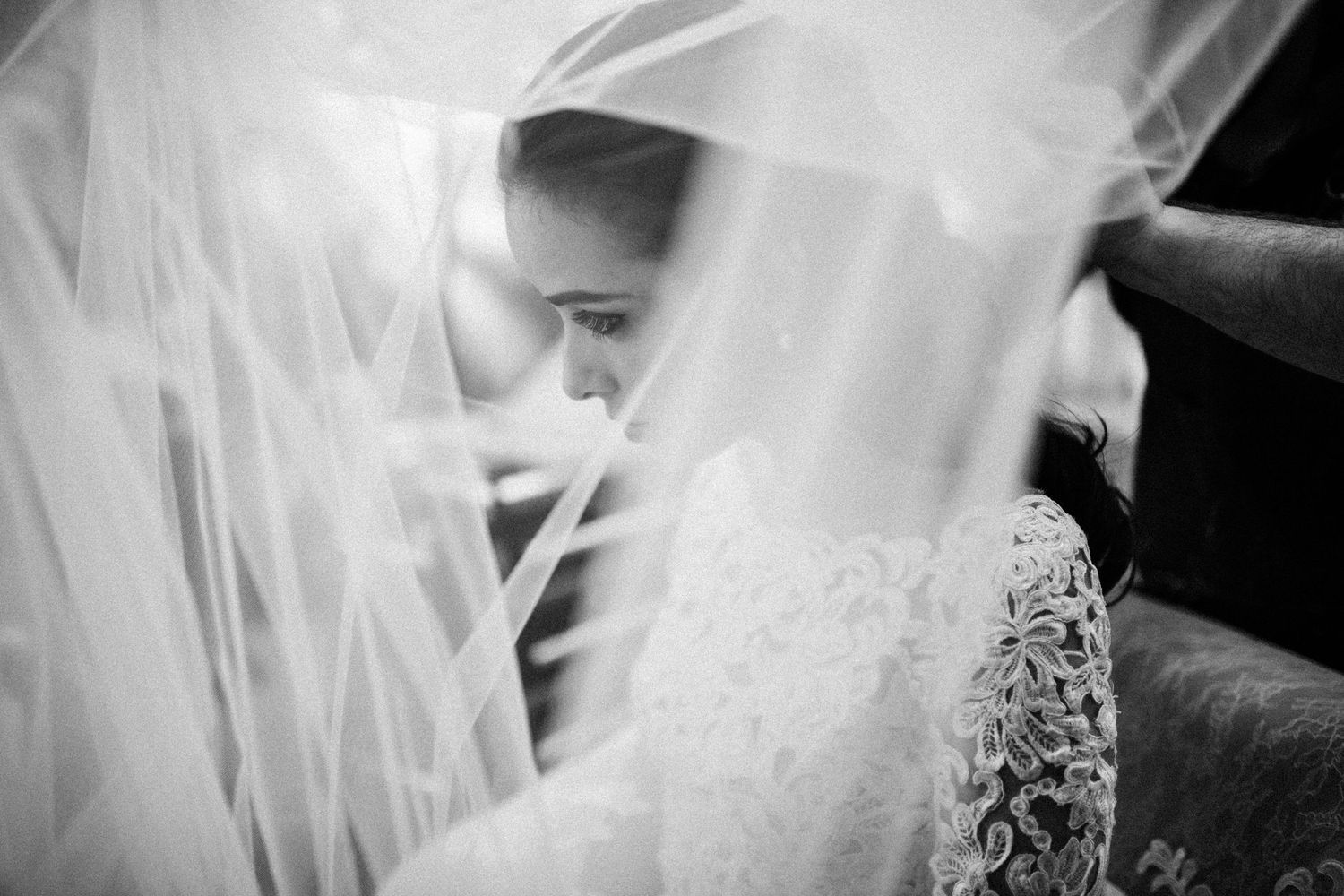 Ethereal close-up of flowing white wedding veil with lace details.