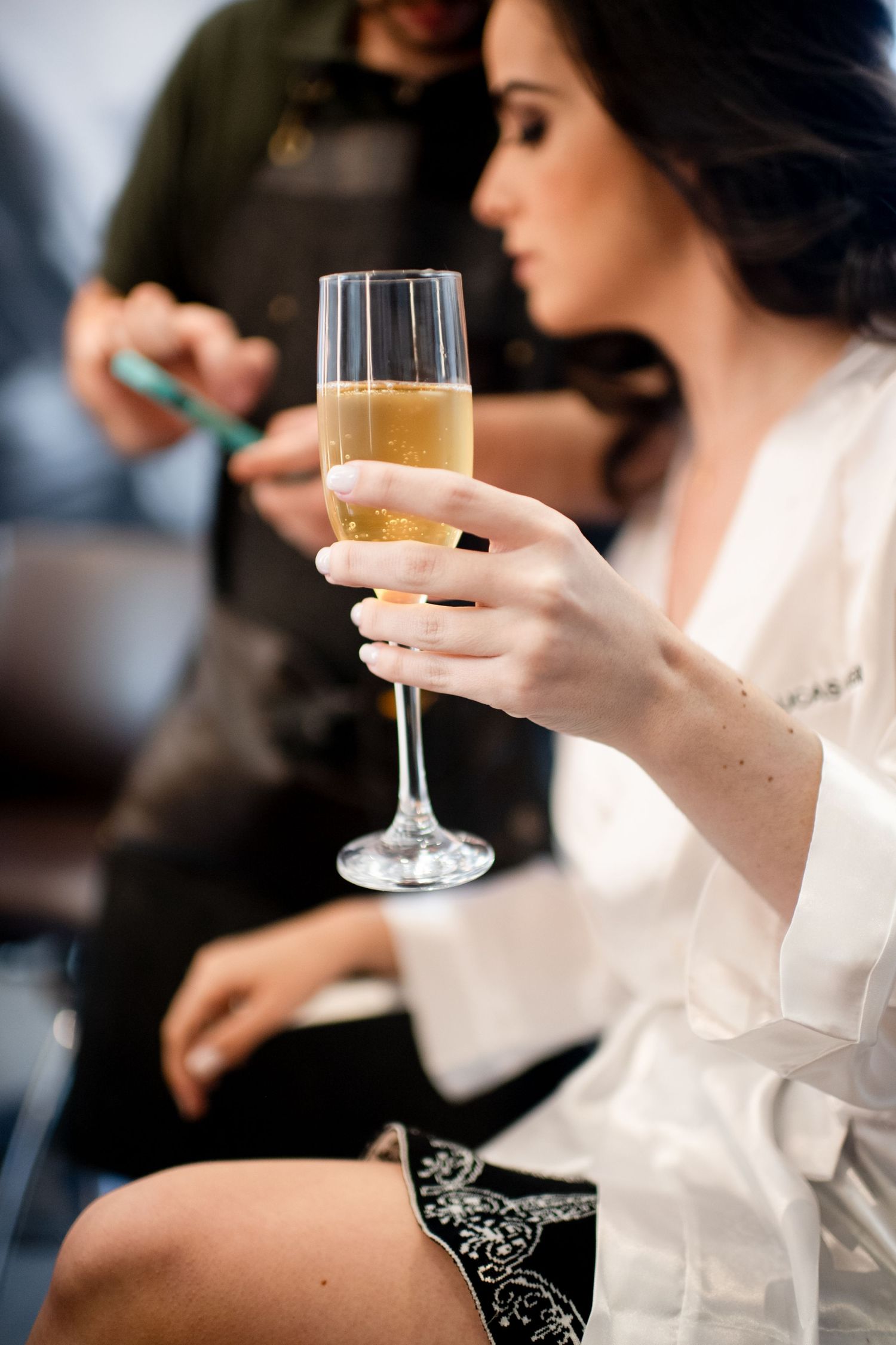 Close-up of hands holding champagne glasses during wedding preparations.