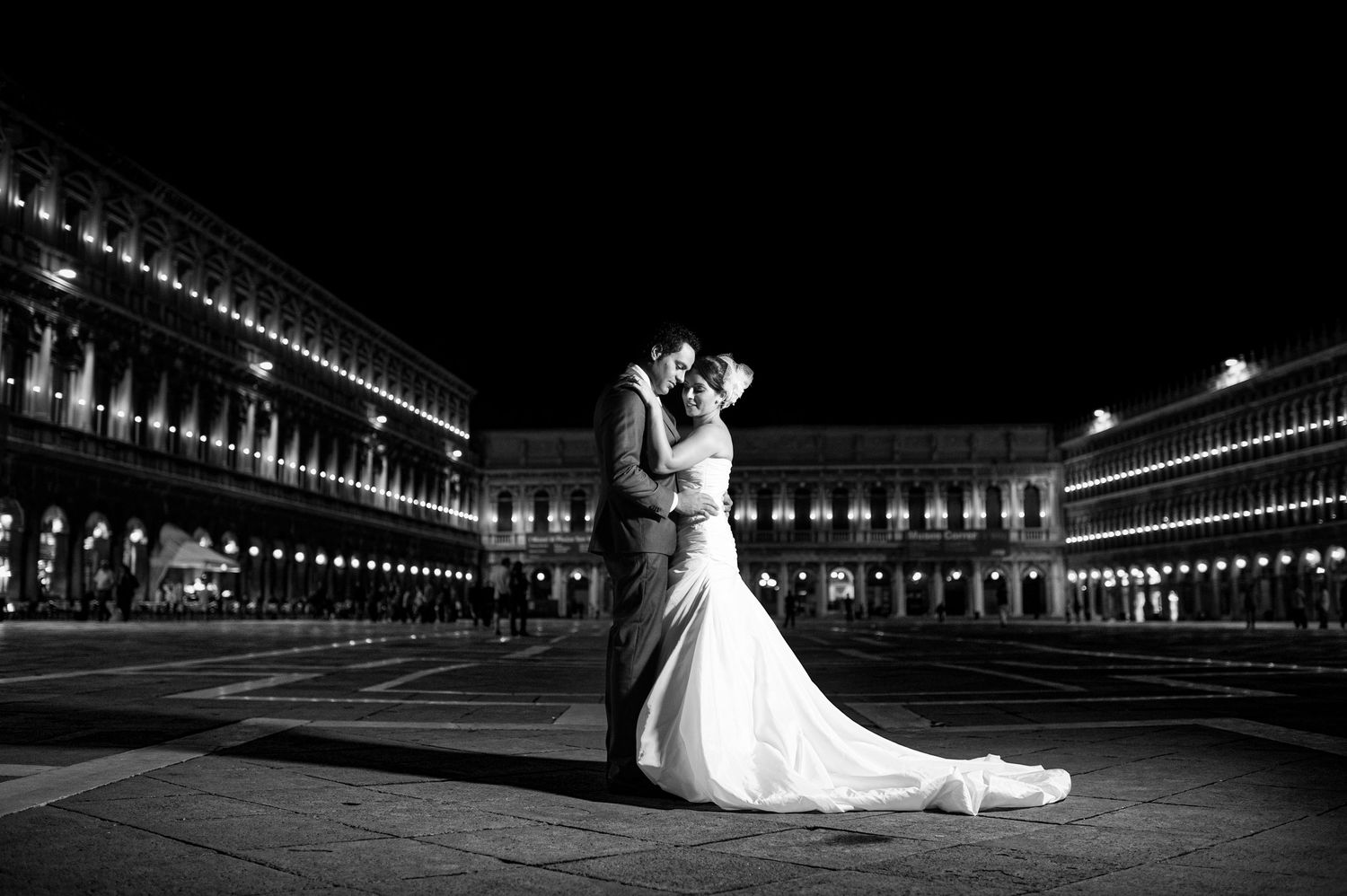 Dramatic black and white wedding photo with string lights creating a tunnel effect.