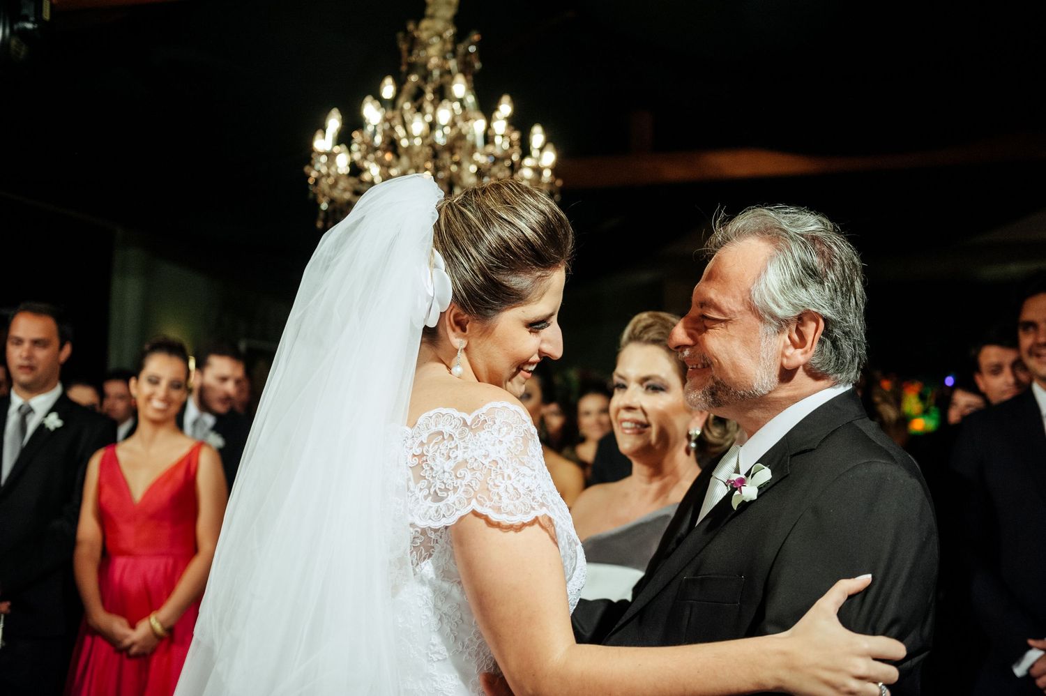 Emotional wedding ceremony moment under ornate chandelier lighting.