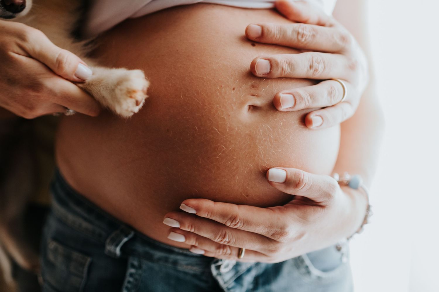 Close-up shots of hands tenderly placed on a pregnant belly.