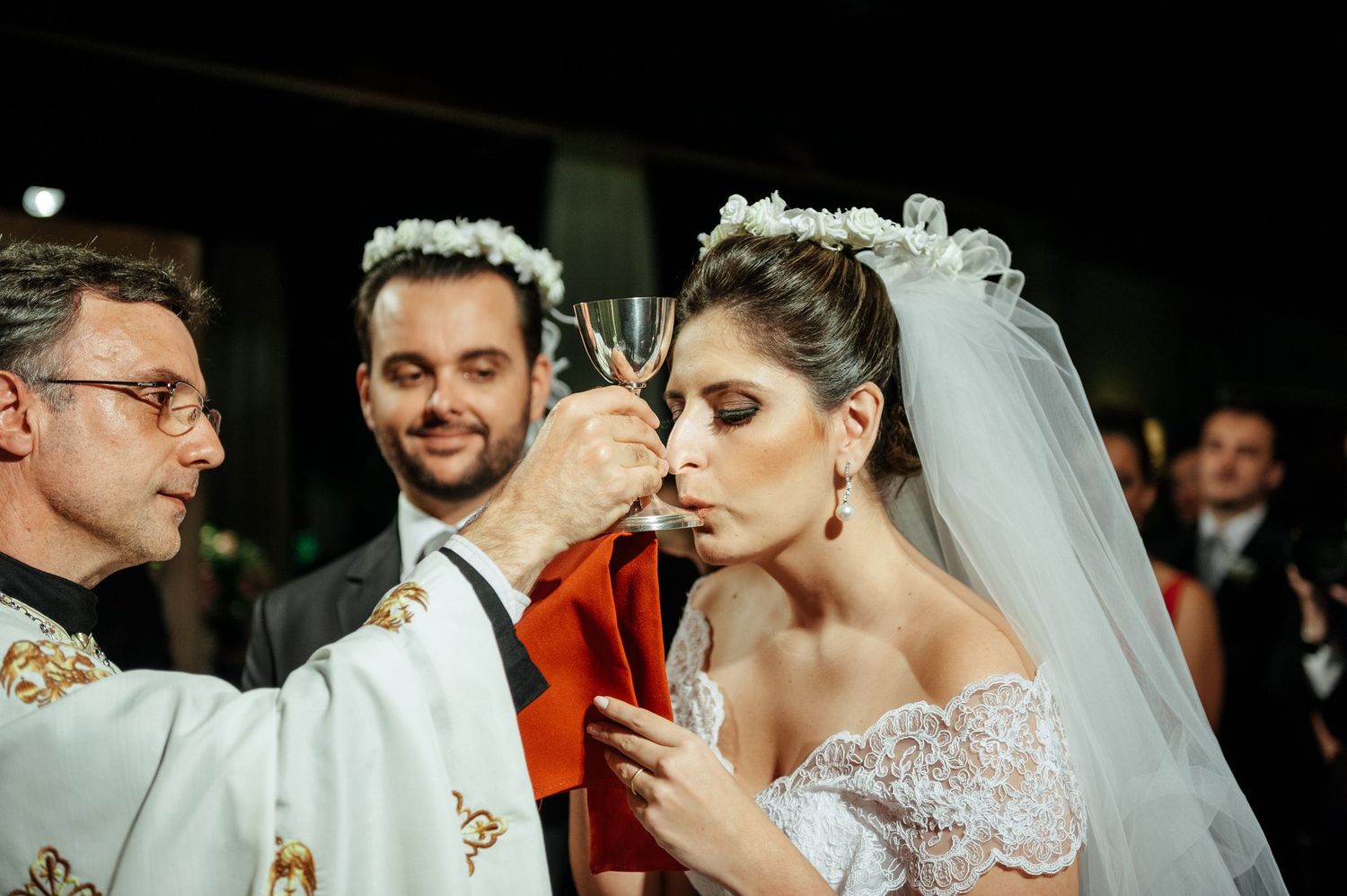 Wedding celebration moments captured in dark reception venue with candlelit ambiance.