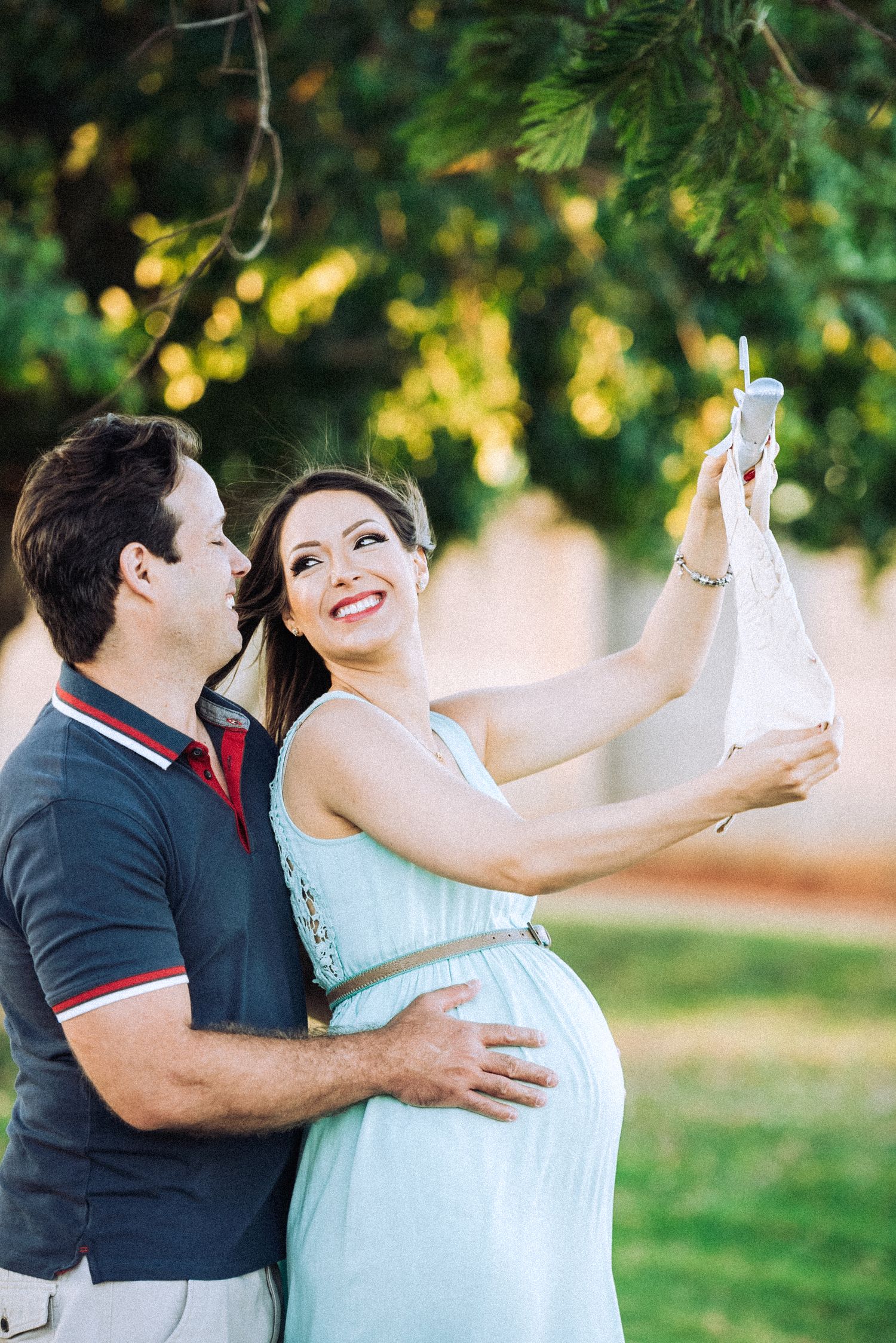 Couple sharing joyful moment during outdoor maternity photoshoot.