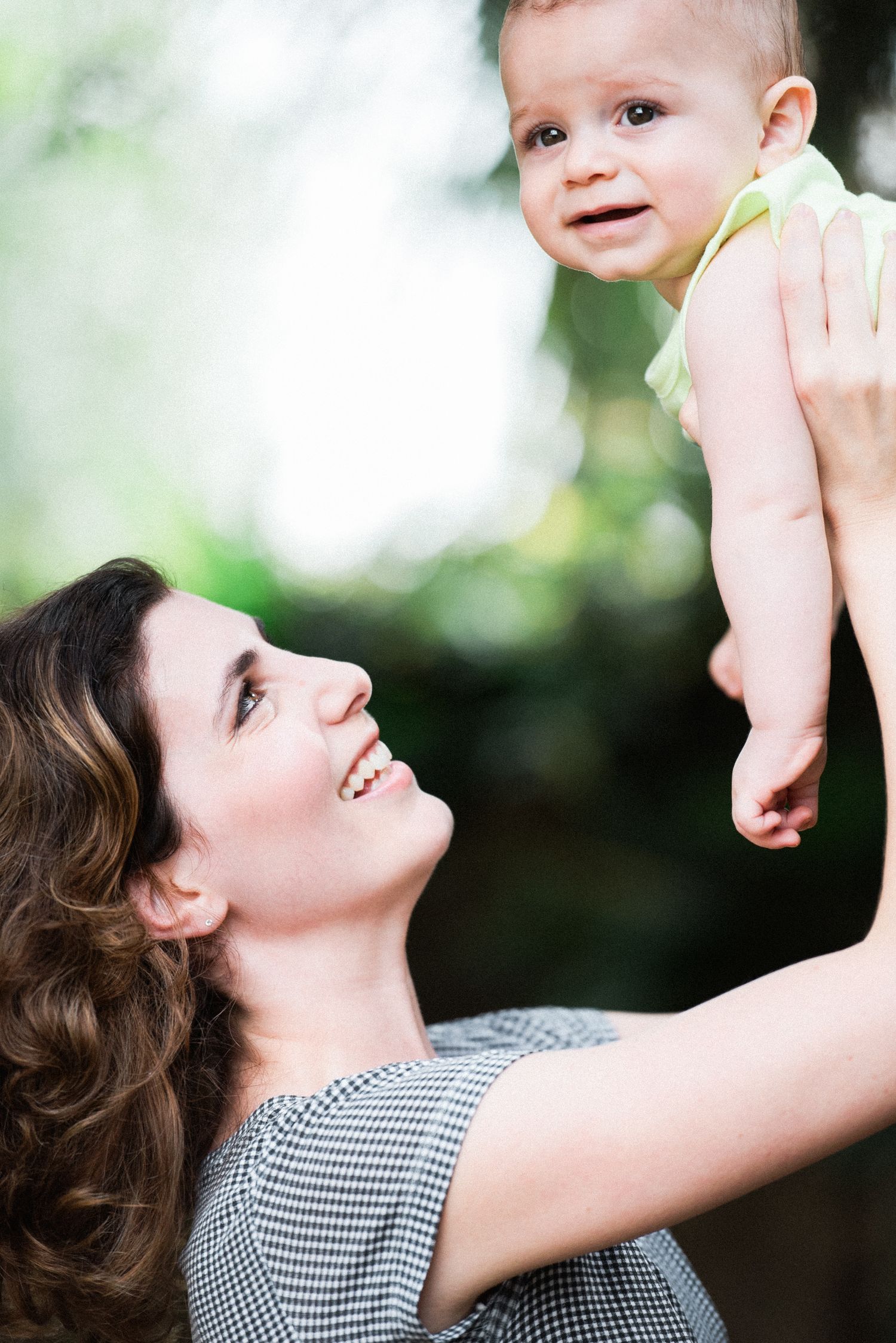 Joyful playtime moment captured in outdoor setting with checkered pattern dress.