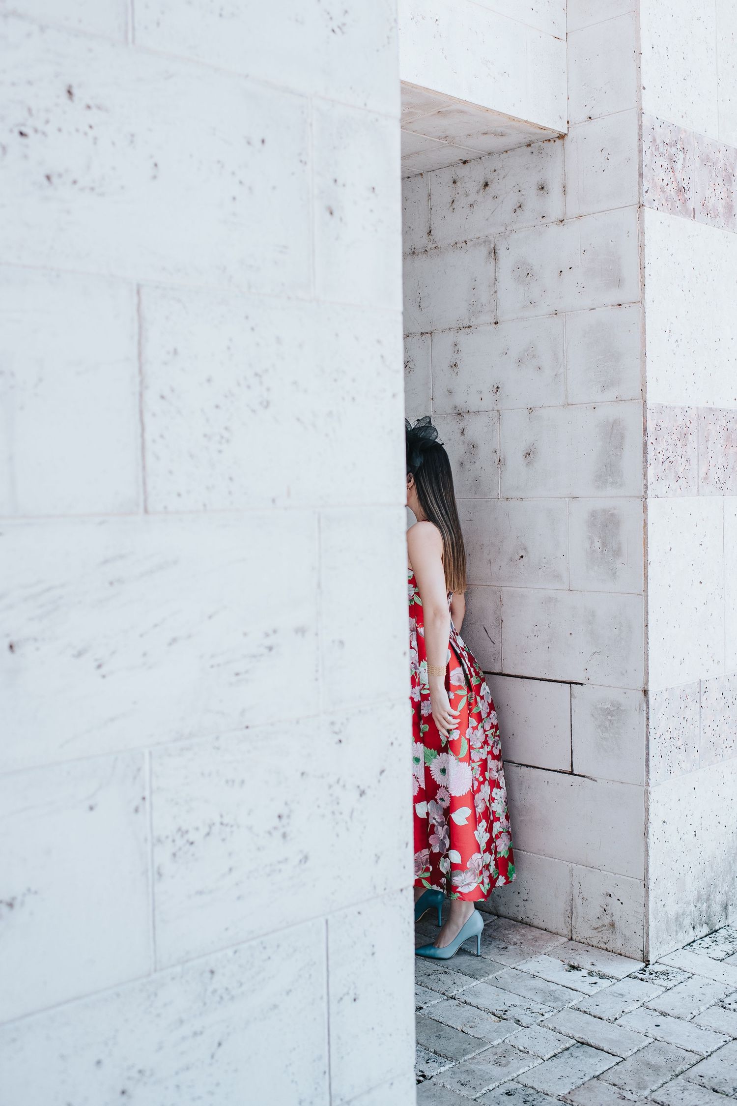 White marble walls frame a glimpse of red floral fabric in an architectural setting.