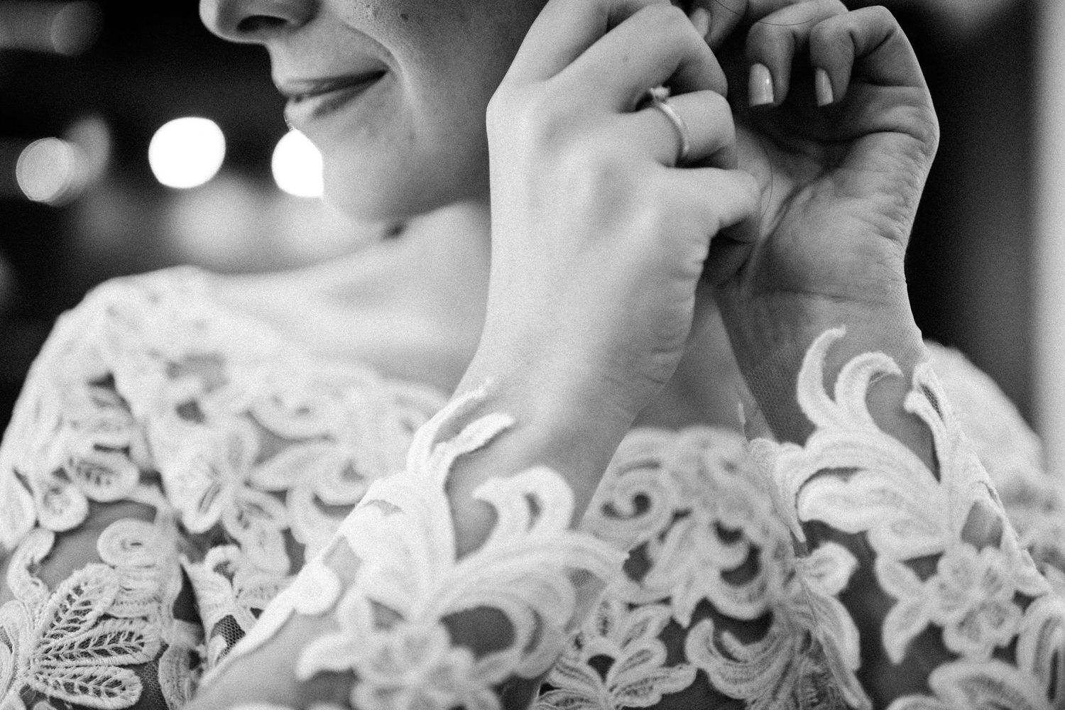 Close-up black and white detail of intricate lace wedding dress pattern.
