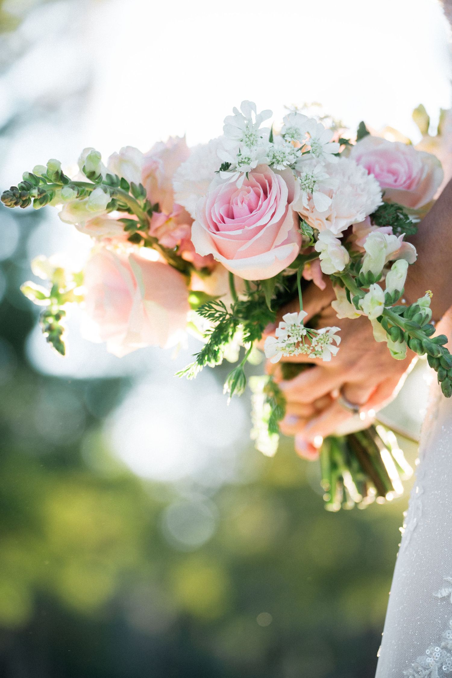 Delicate pink and white wedding flowers with greenery in soft natural light.