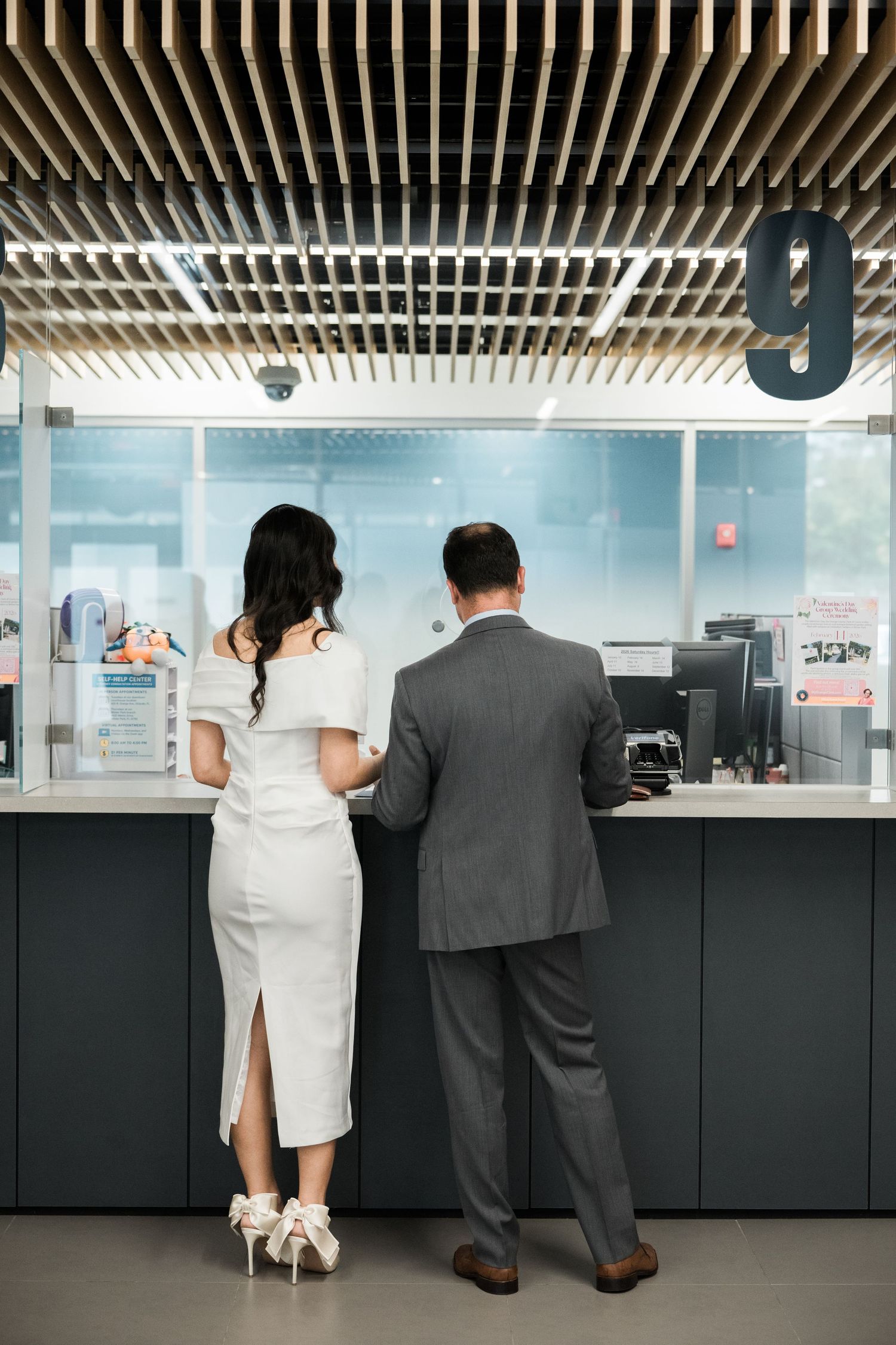 Modern office interior with couple at service counter under geometric ceiling design.