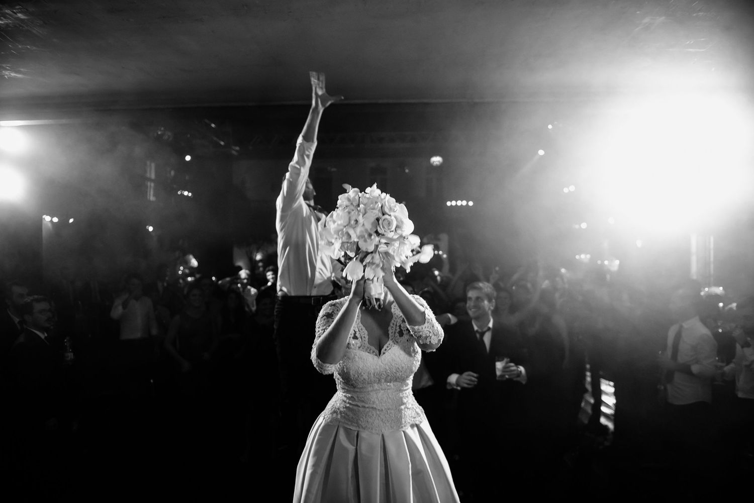 Atmospheric black and white shot of a wedding dance floor with dramatic lighting.