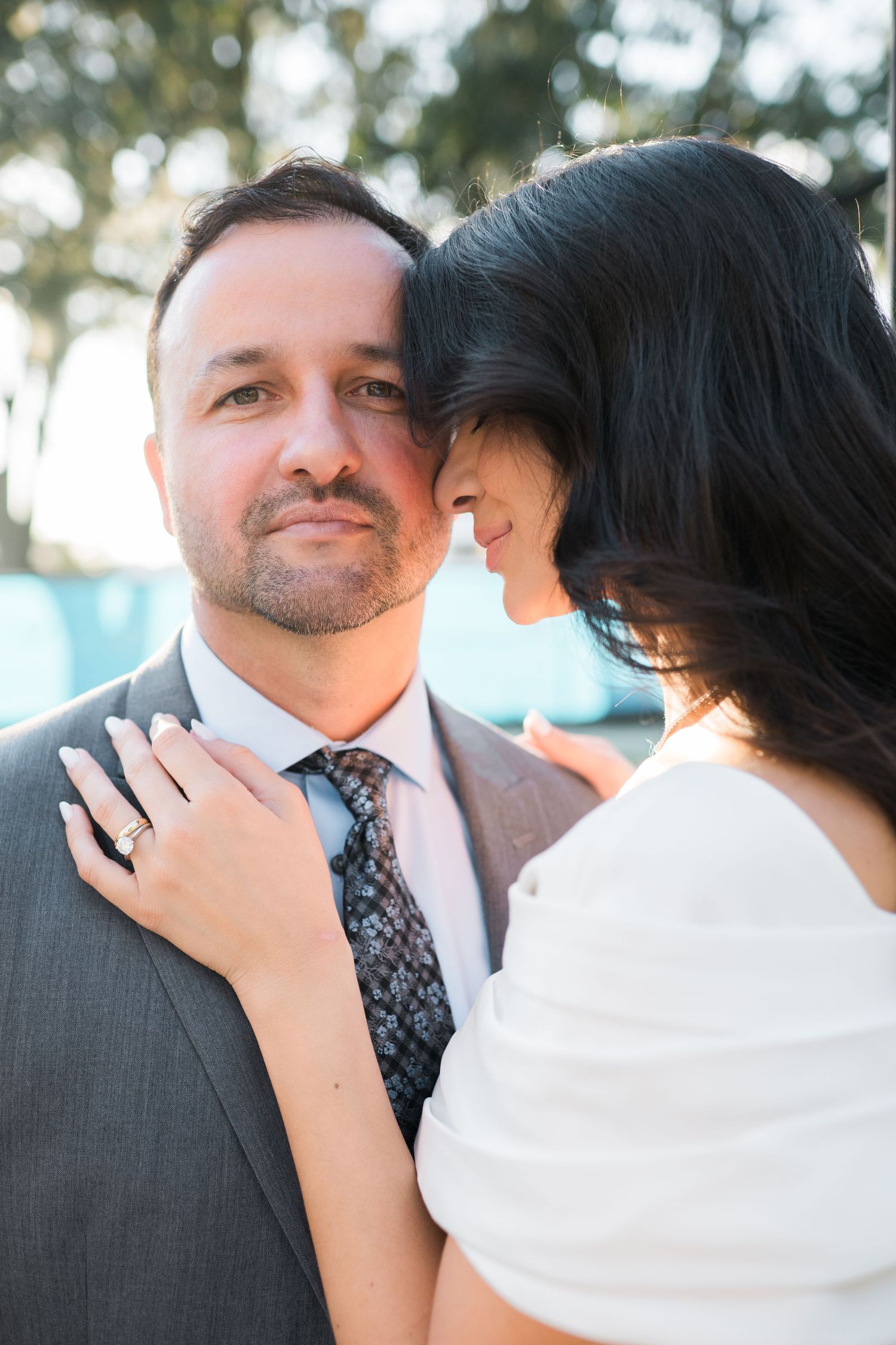 Romantic outdoor portrait of a couple in formal attire sharing an intimate moment.