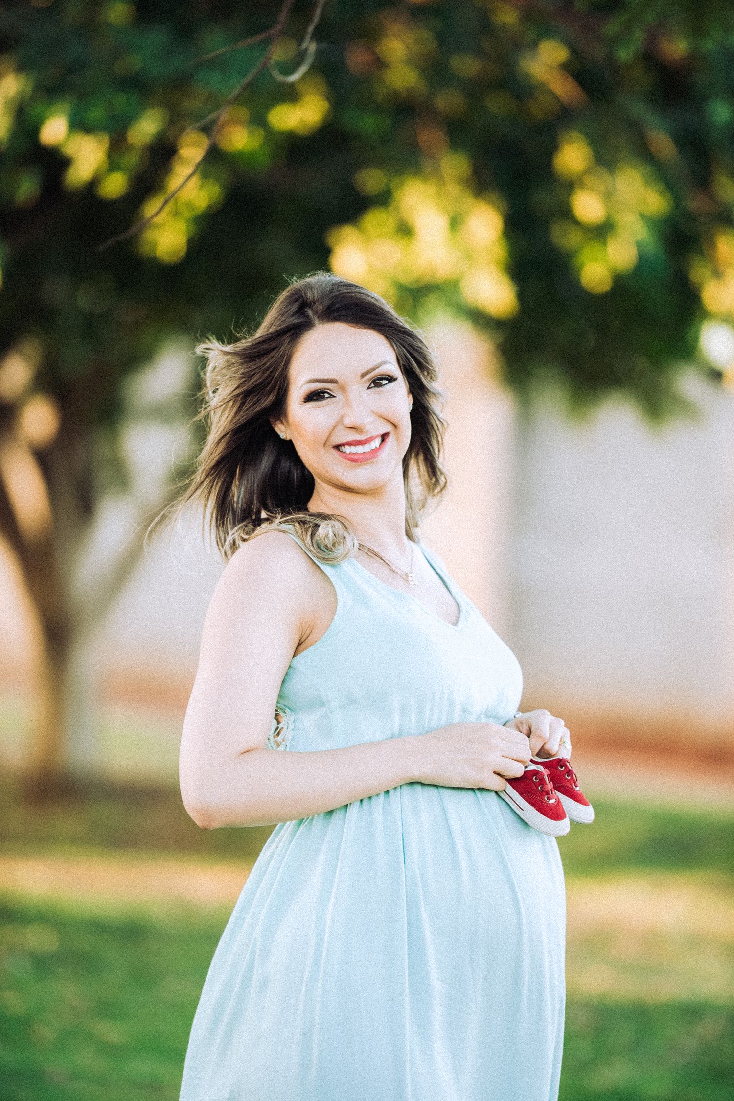 Maternity photo session in mint dress against natural outdoor setting.
