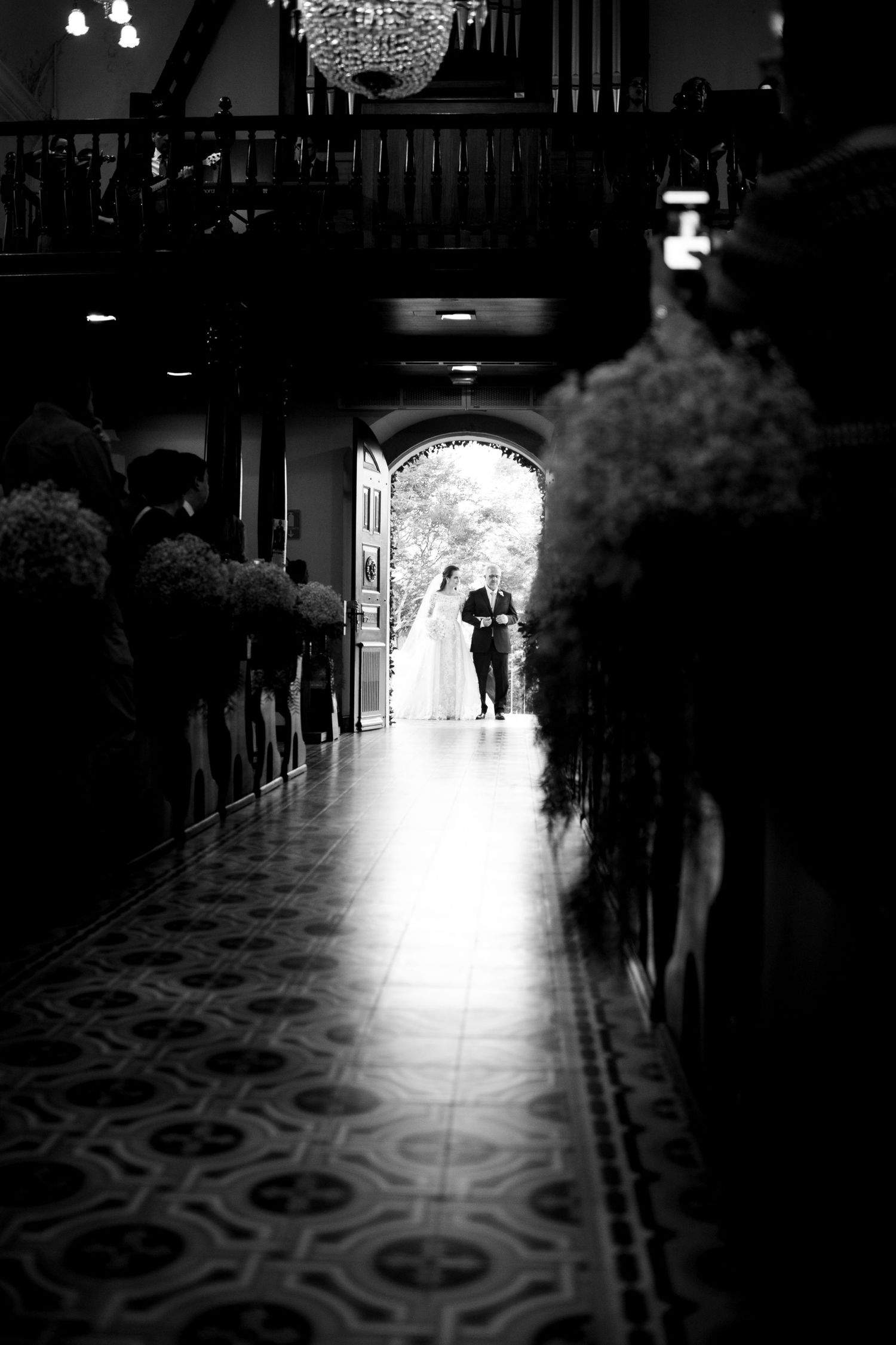 Dramatic black and white wedding ceremony entrance with chandelier and patterned floor.