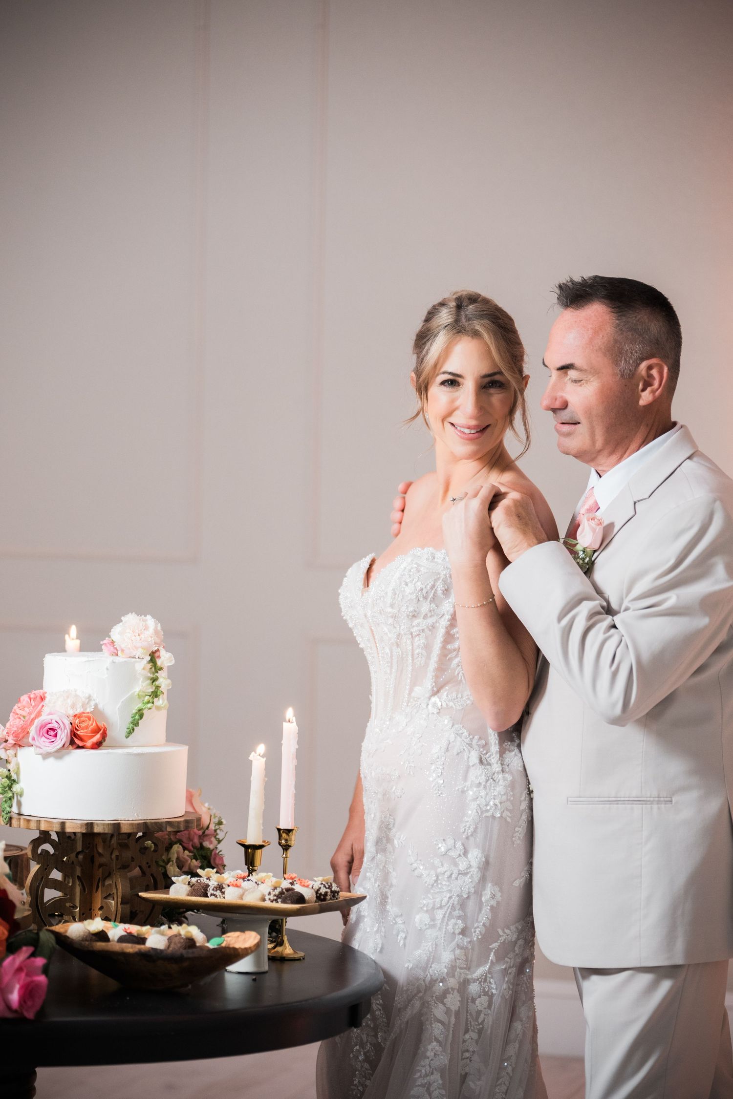Romantic wedding couple sharing a sweet moment next to their elegant dessert display.