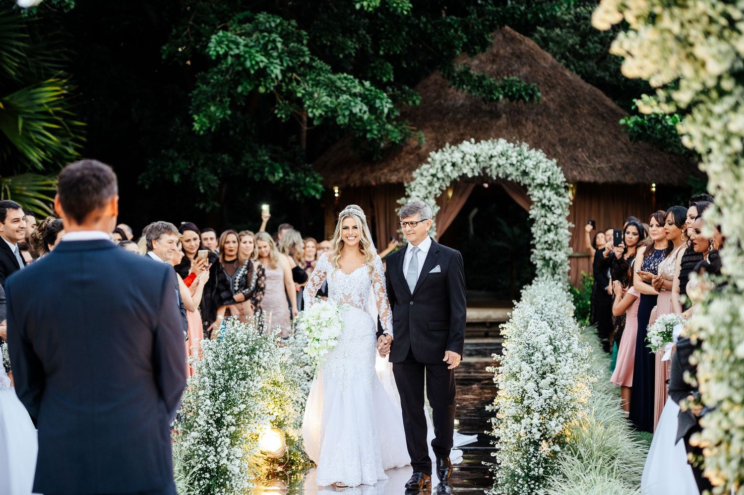 Wedding ceremony setup outdoors with white floral arches and chairs arranged in rows.