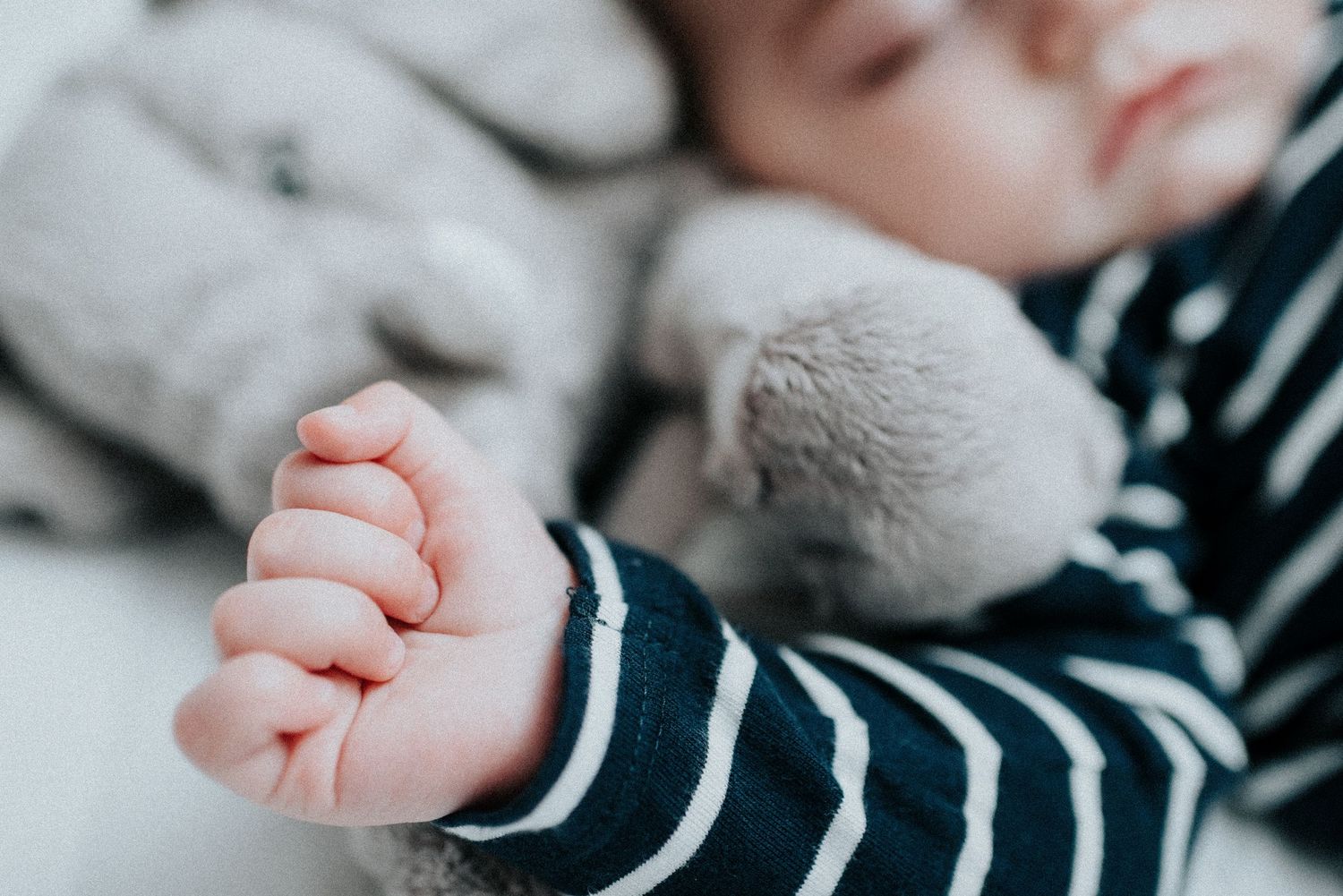 Close-up details of baby's tiny hands and striped sleeves.