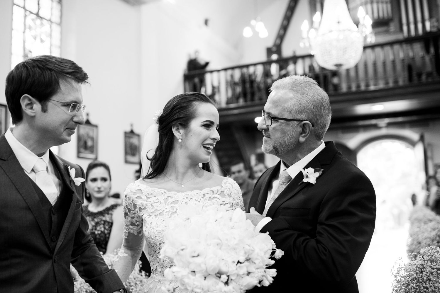 Candid black and white moment captured during wedding ceremony in church setting.