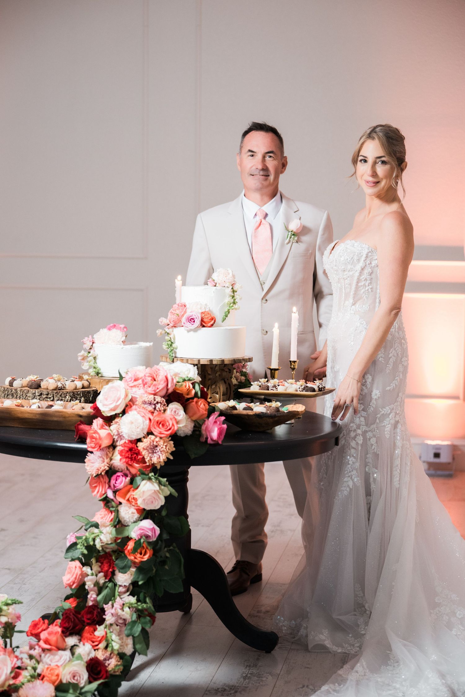 Wedding couple standing beside a beautifully decorated black table with pink floral arrangements.