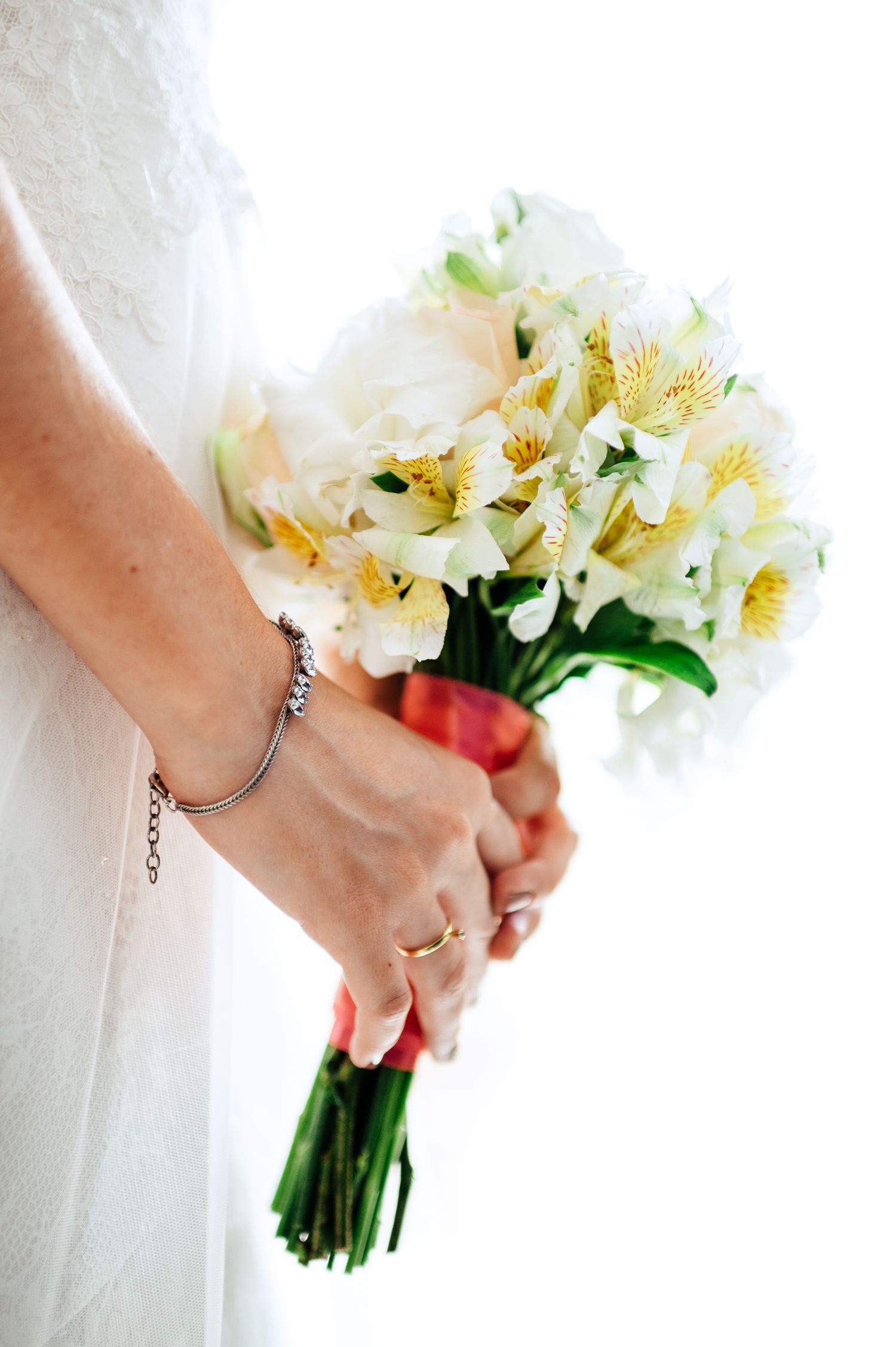Close-up of hands holding an elegant white and cream floral bouquet.
