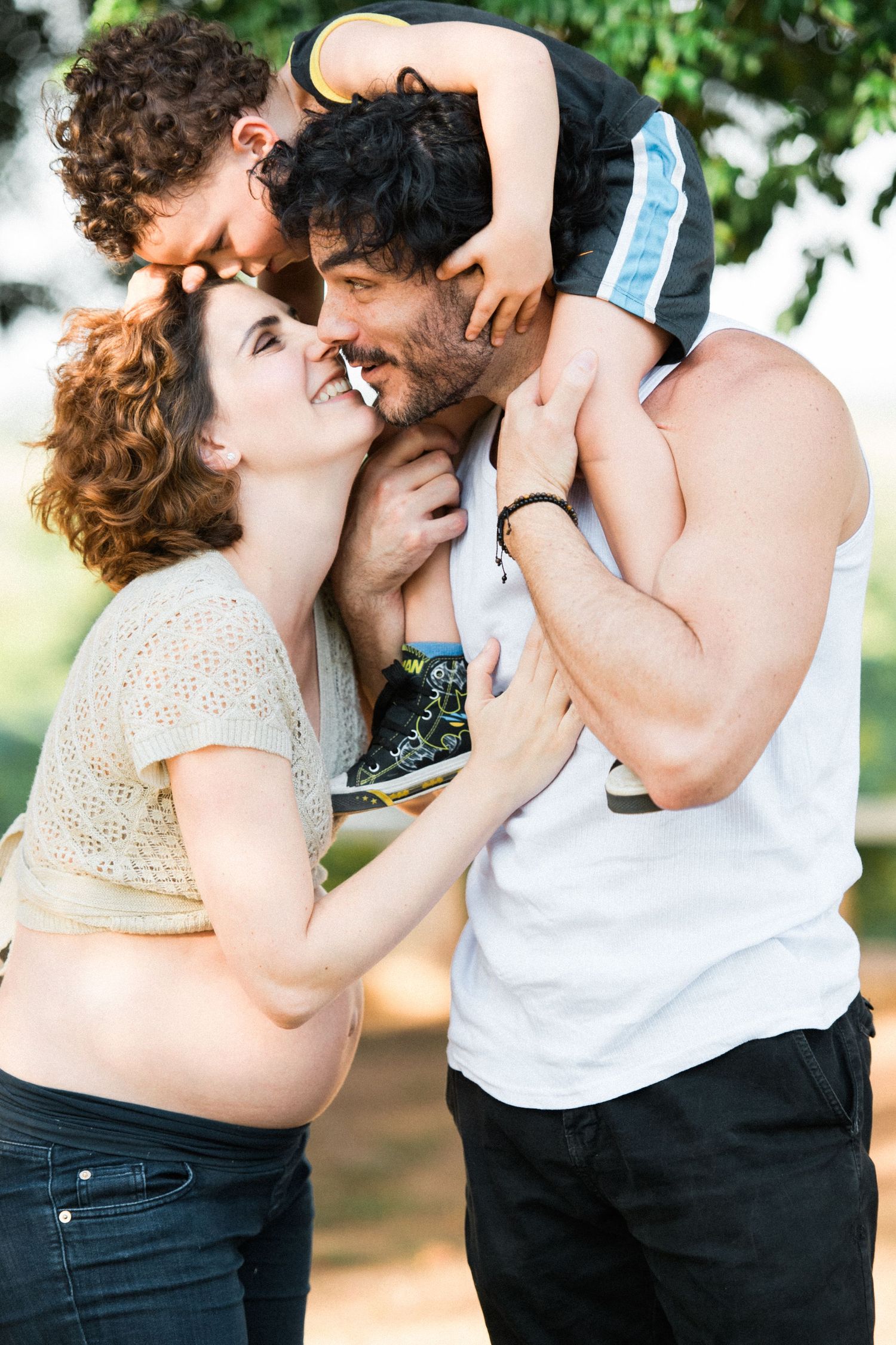 Intimate family portraits showing affectionate moments outdoors on a sunny day.