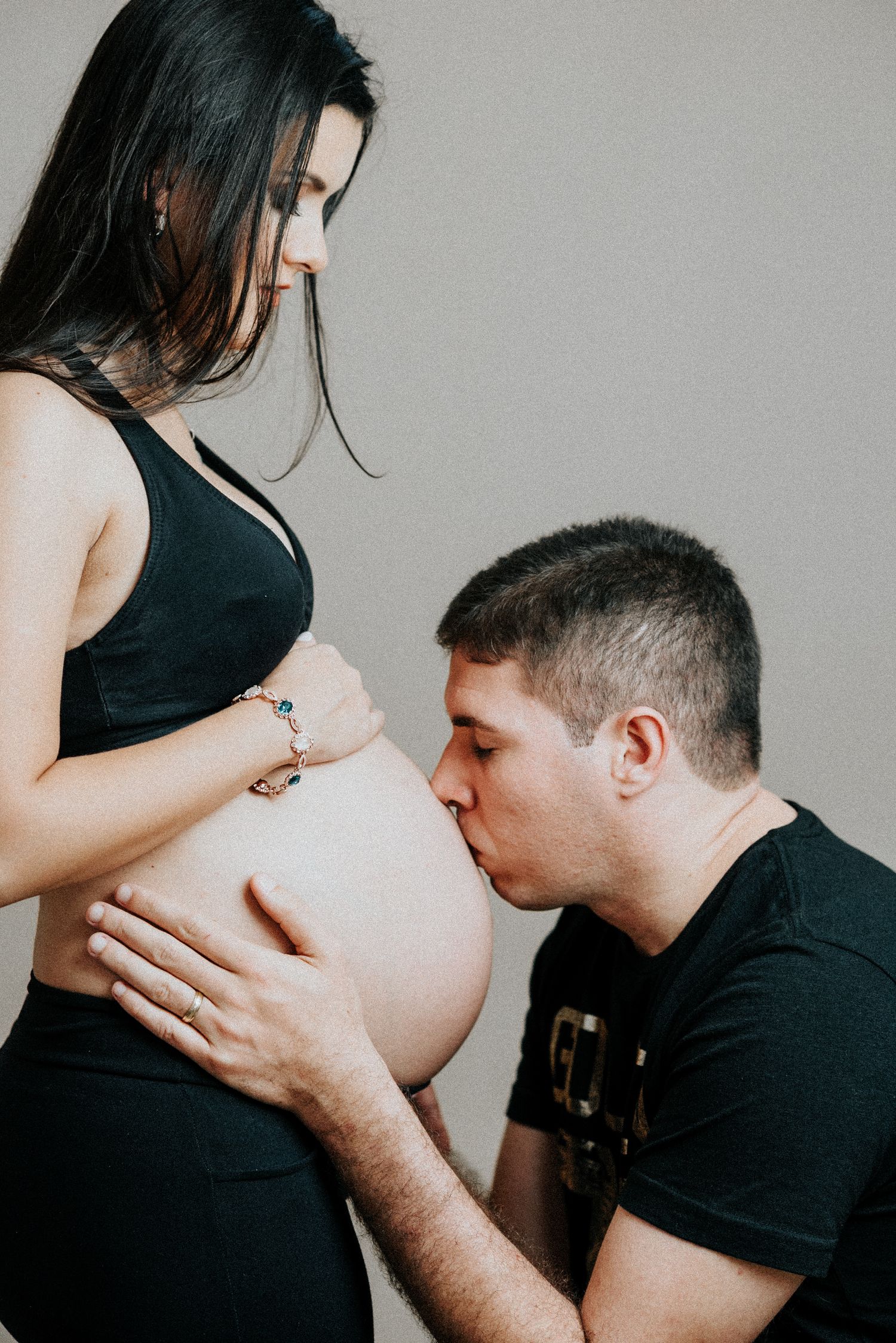 A series of intimate maternity photos showing tender moments and kisses against a gray background.