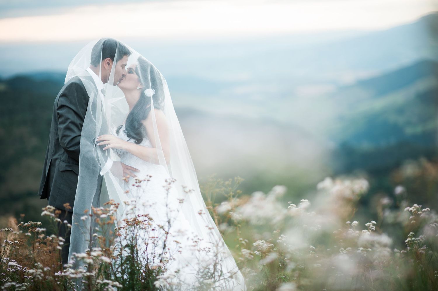Scenic mountain landscape wedding photography with flowing veil against misty natural backdrop.