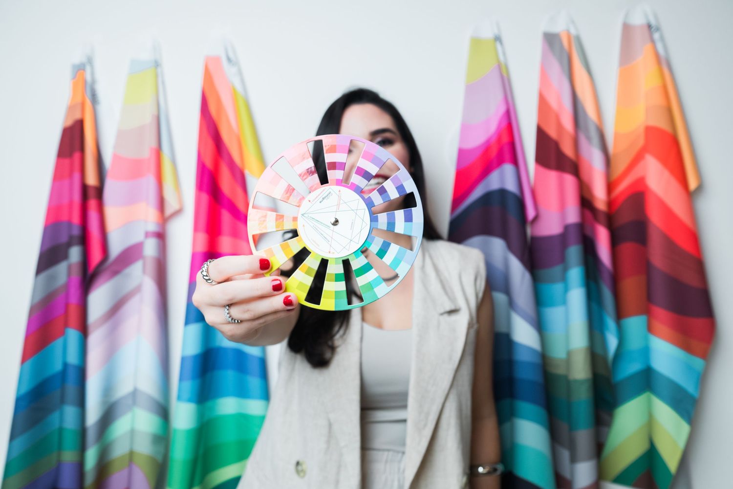 A colorful rainbow silk scarf is displayed in multiple ways against a white background.