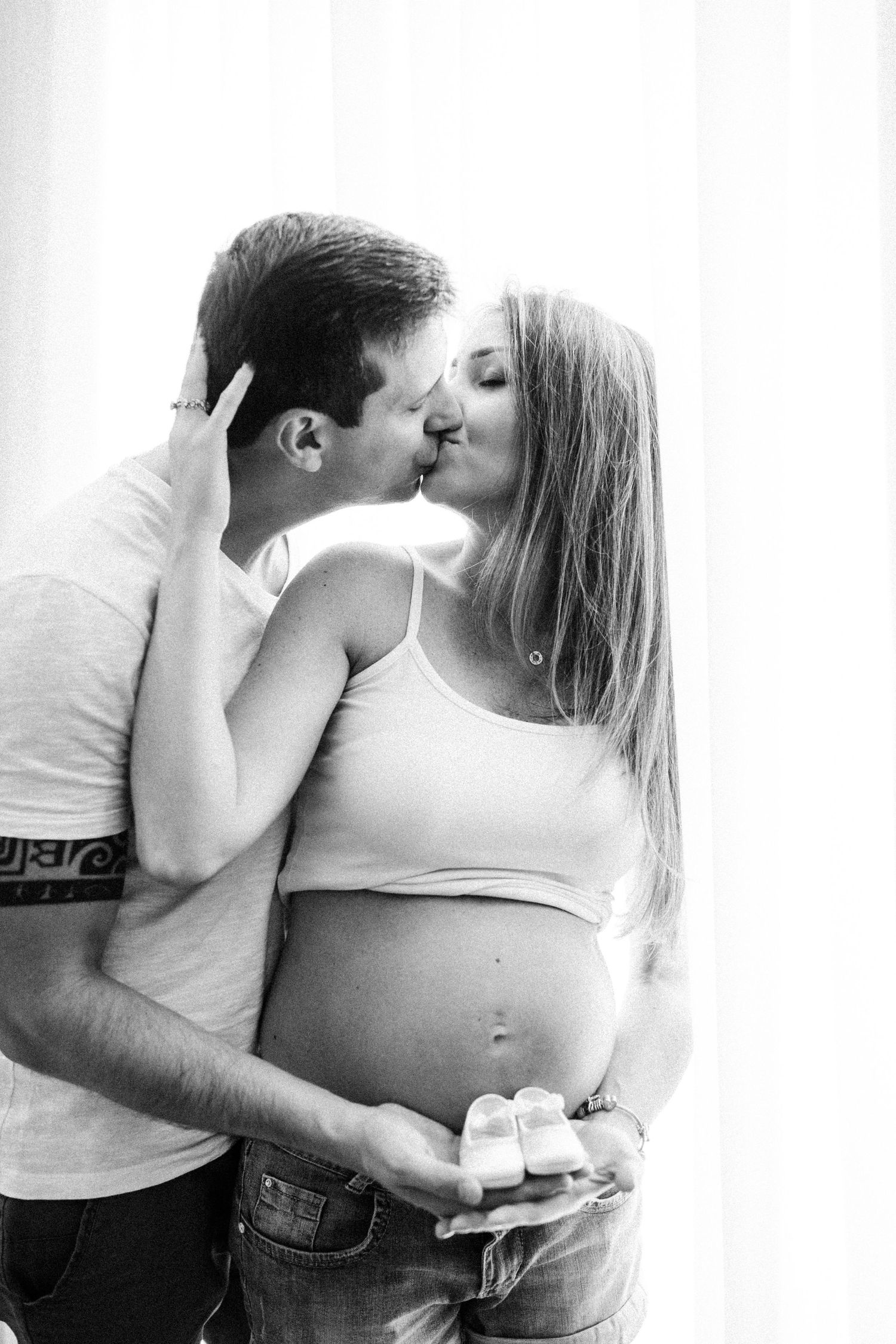 Intimate black and white pregnancy photos of couple sharing tender moments.
