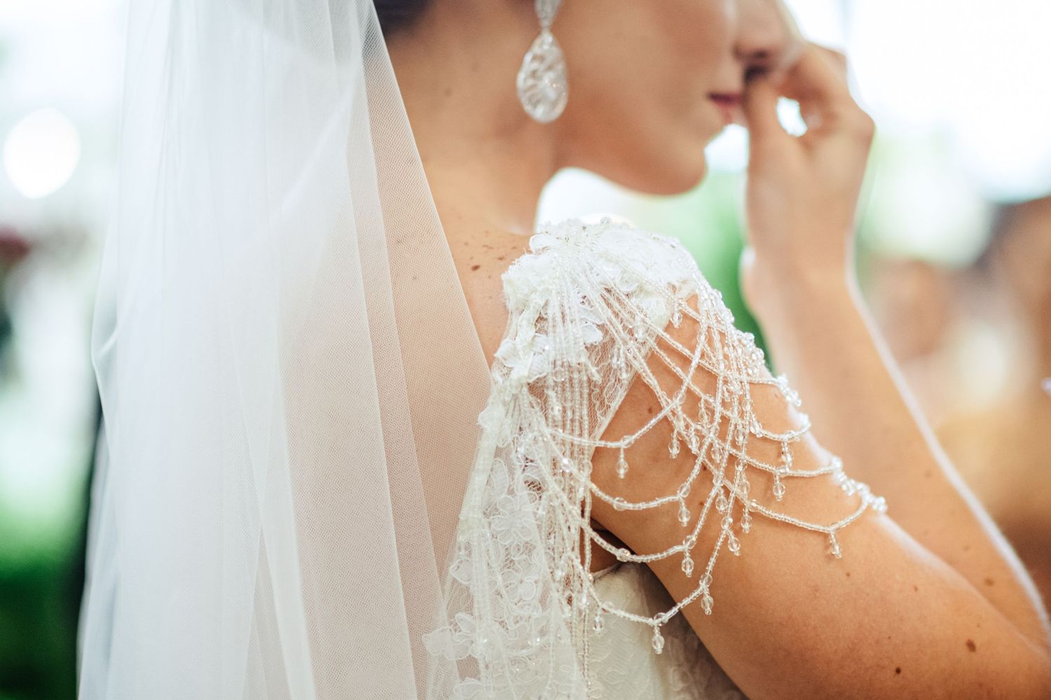 Close-up of intricate pearl and lace details on wedding attire.