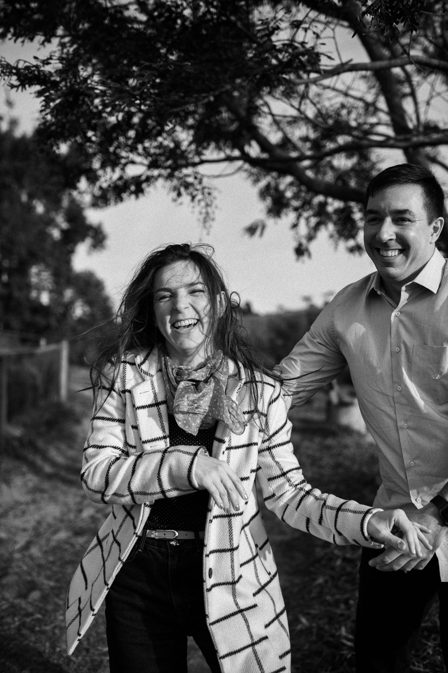 Joyful moment captured in black and white against natural outdoor setting.