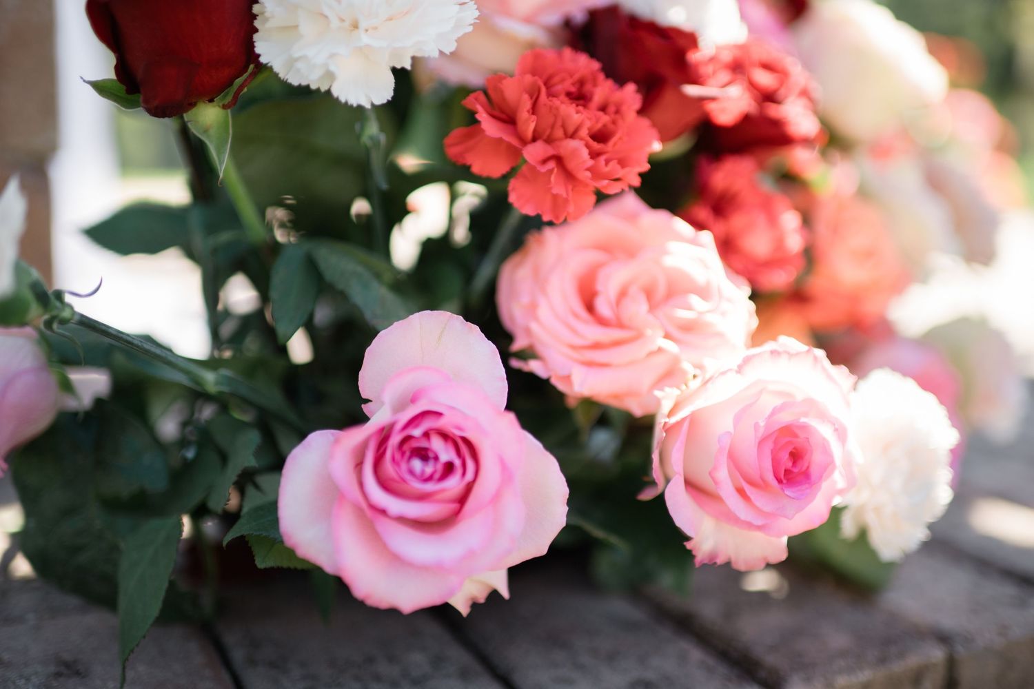 Close-up of pink and coral roses with delicate petals in a wedding floral arrangement.