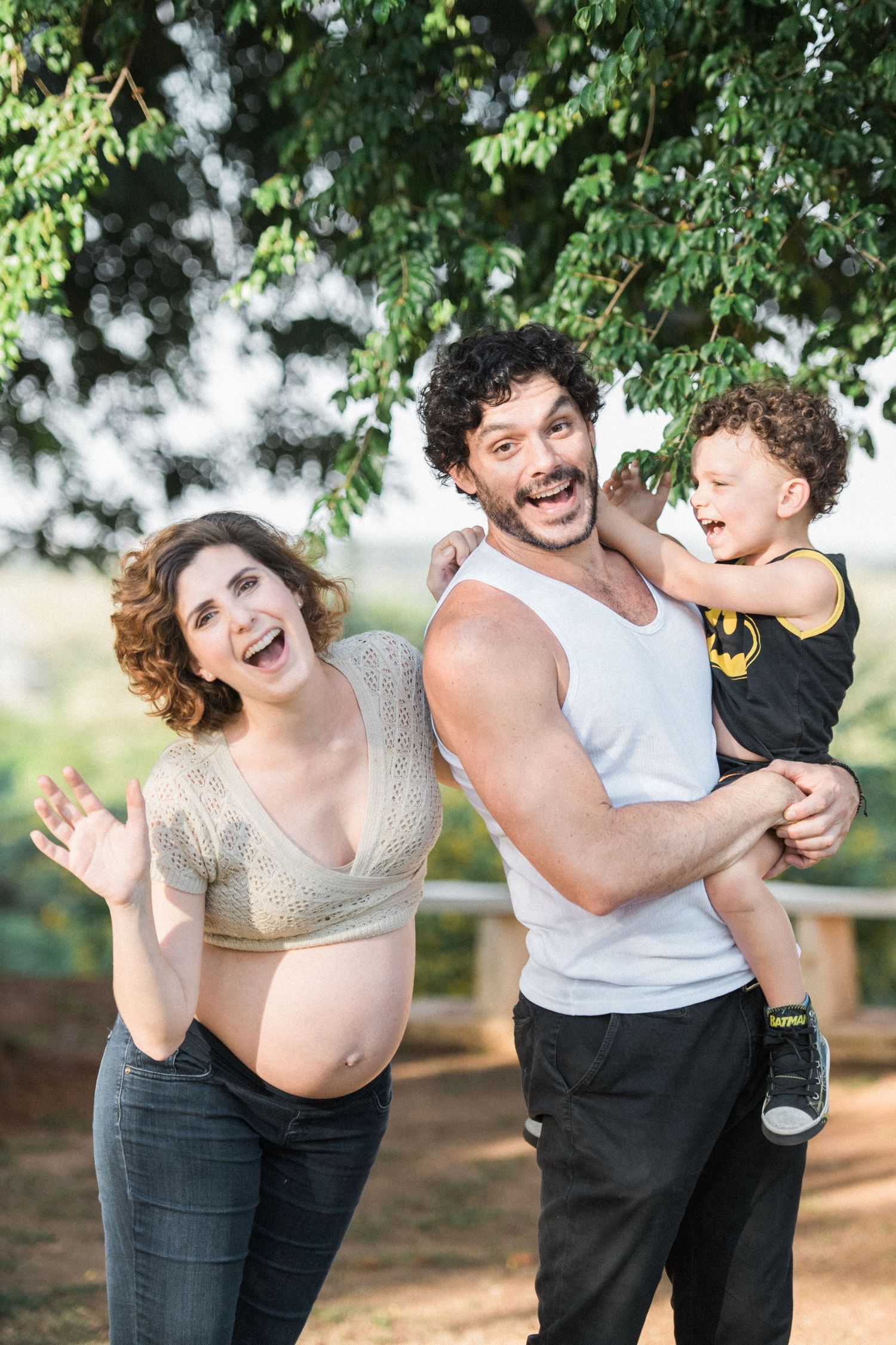 Candid moments of laughter and joy between adults and child in an outdoor setting.