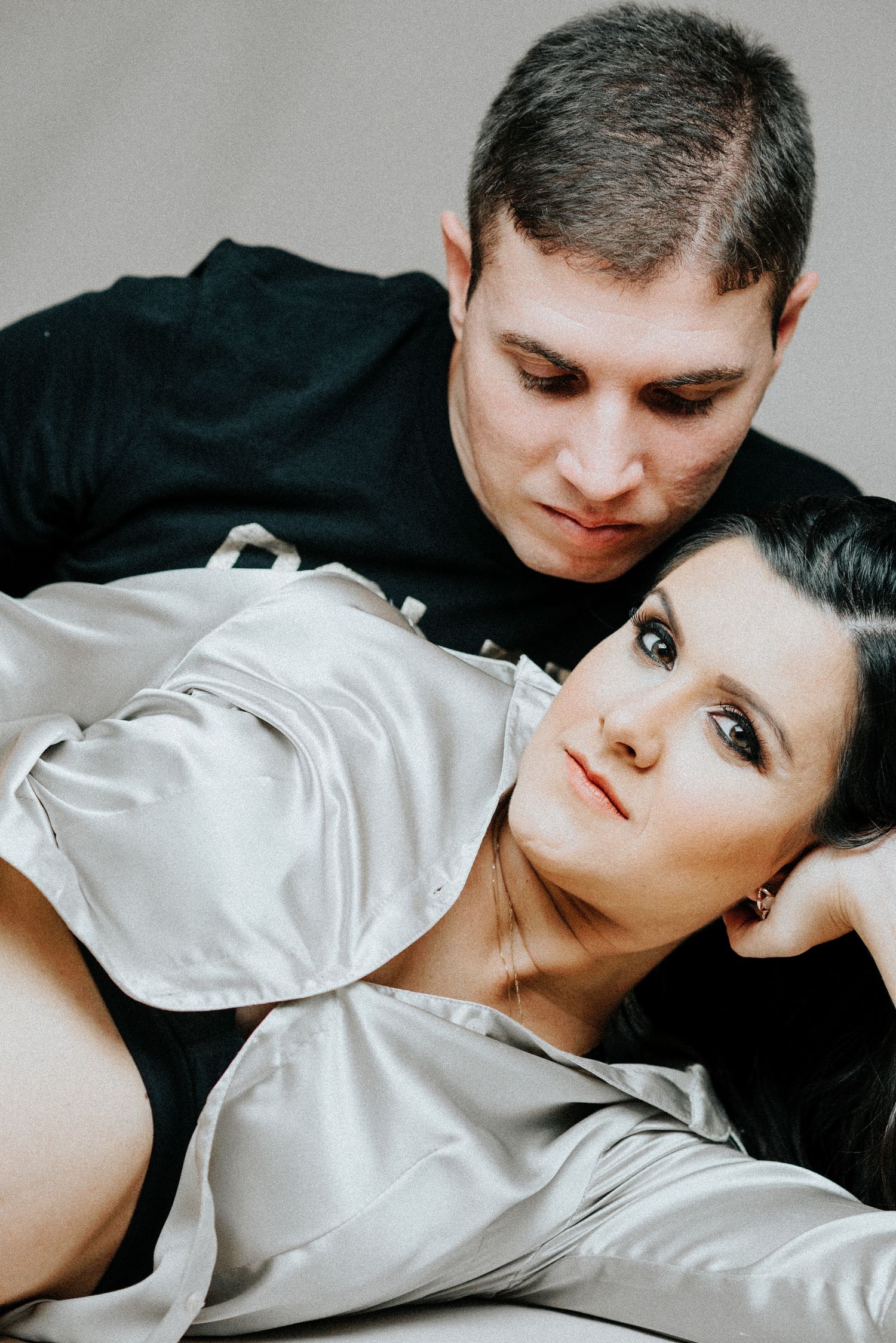 Intimate maternity portrait with couple against grey background.