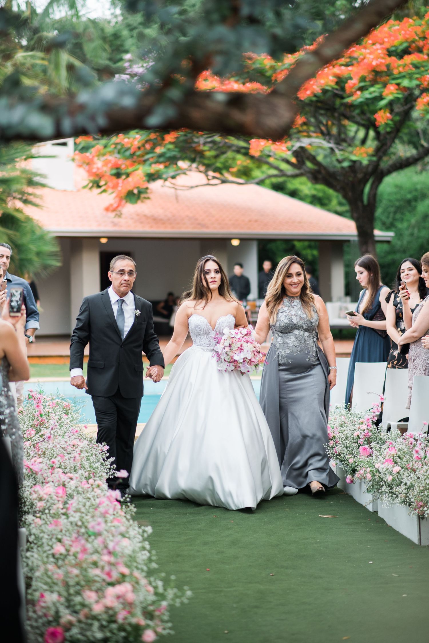 Wedding party walking outdoors with colorful flowers and greenery in the background.