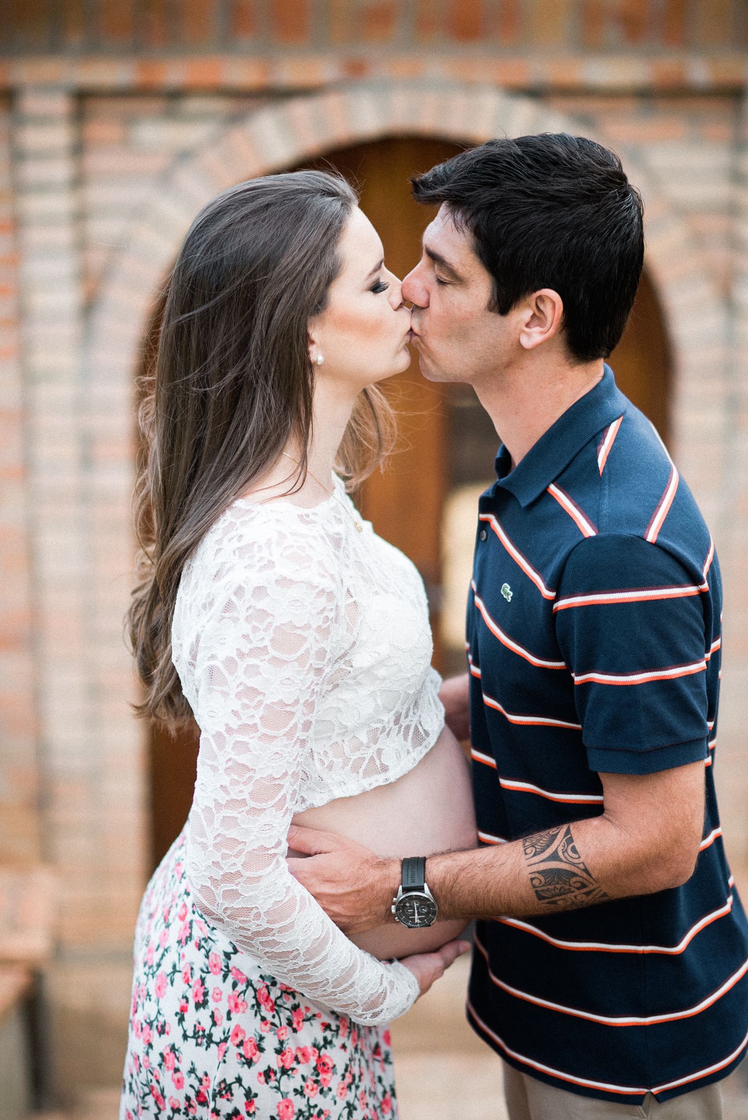 Romantic couple sharing tender moments against a rustic brick wall background.