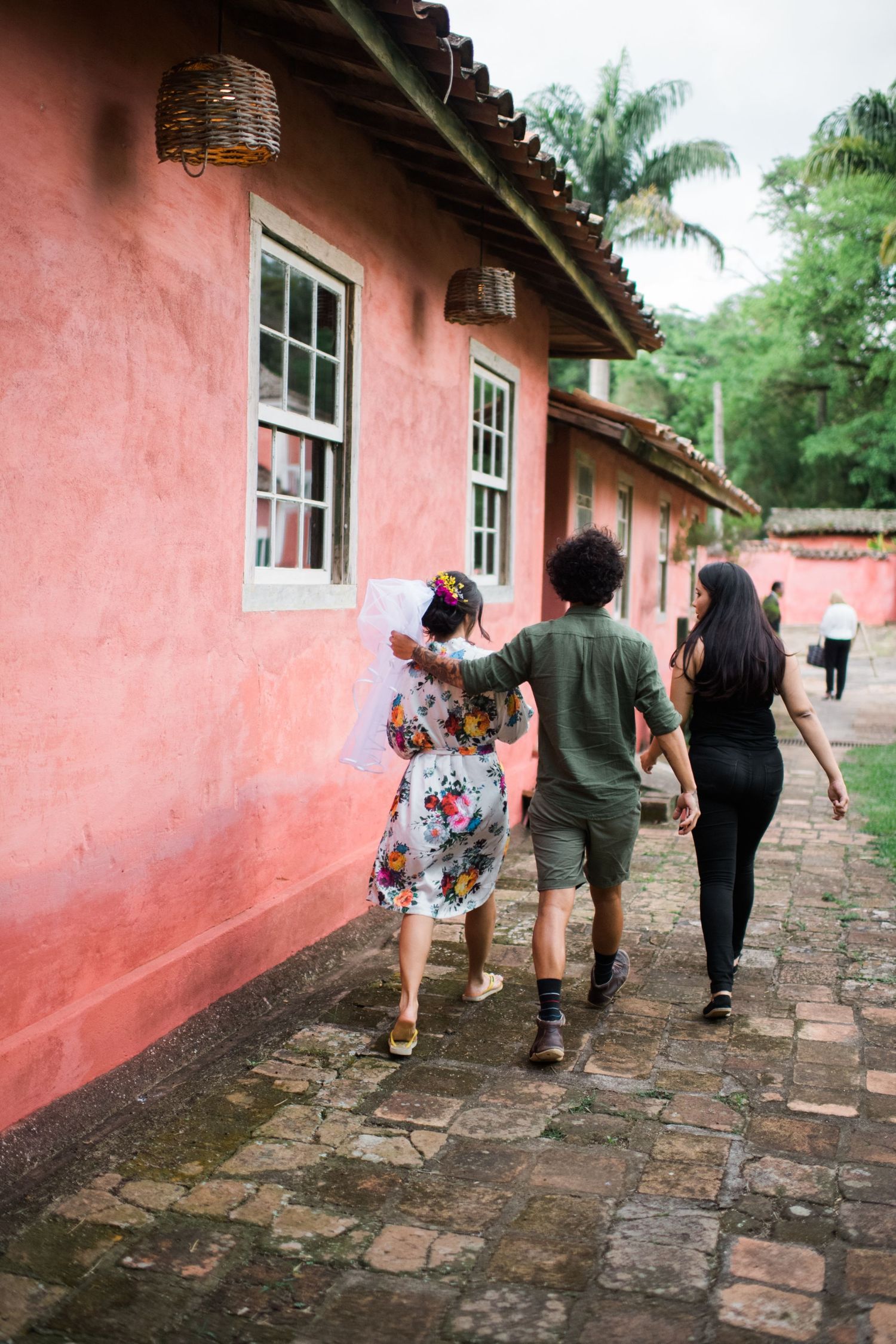 Group walking along a rustic cobblestone path beside a pink colonial wall.