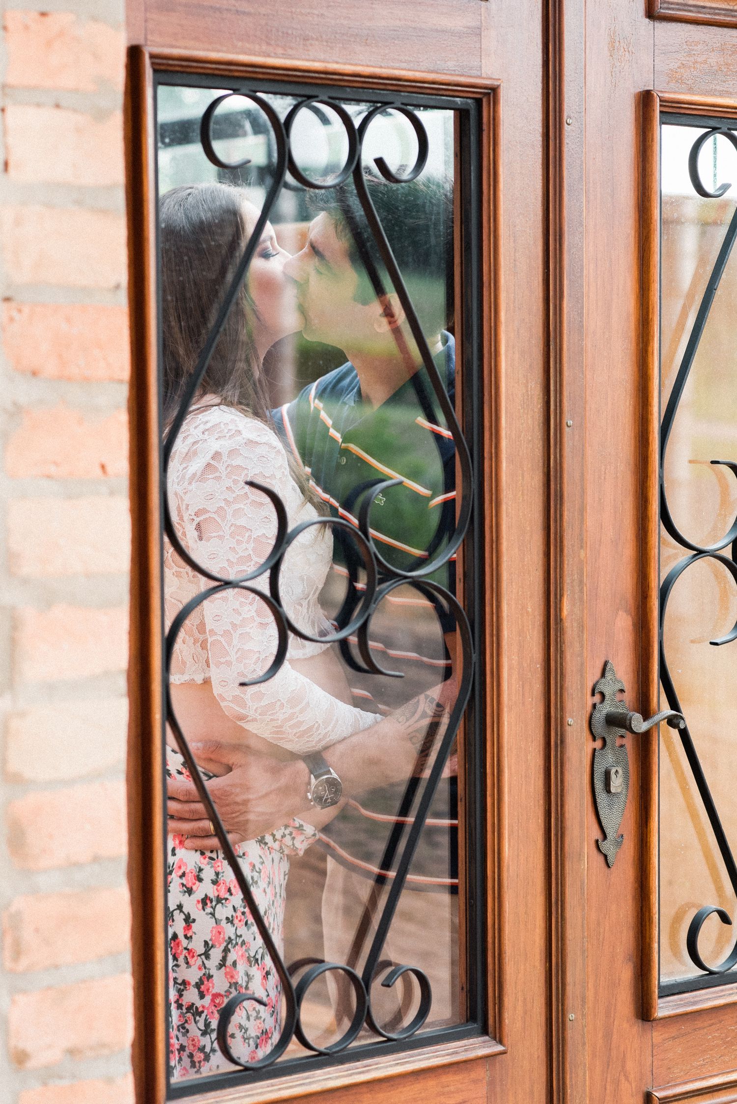 Decorative wooden doors with ornate iron window details and brick walls.