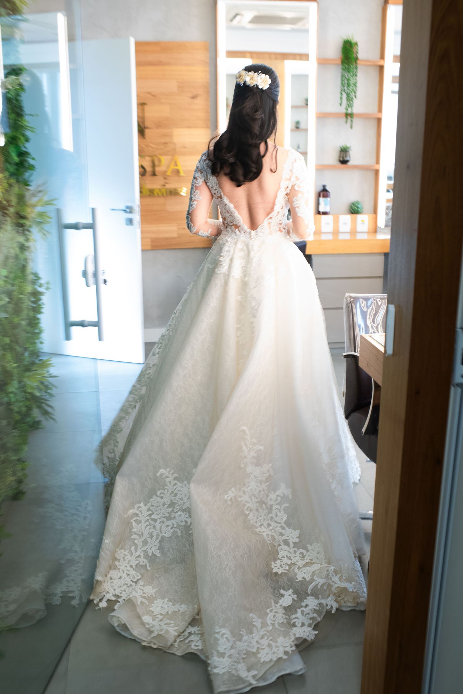 Full-length view of an elegant white lace wedding gown with train in natural lighting.