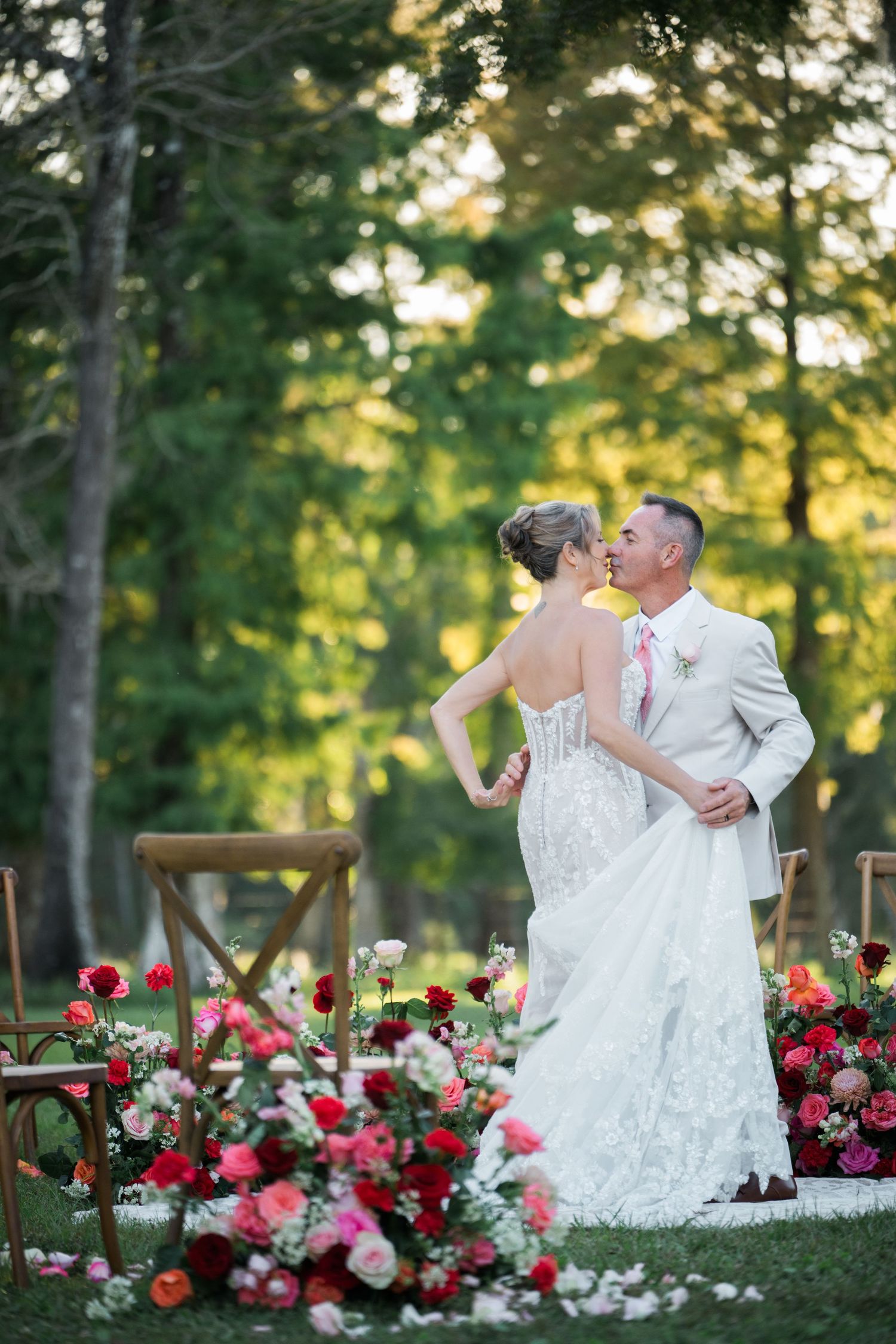 Elegant outdoor wedding scene with beautiful red and pink floral arrangements.