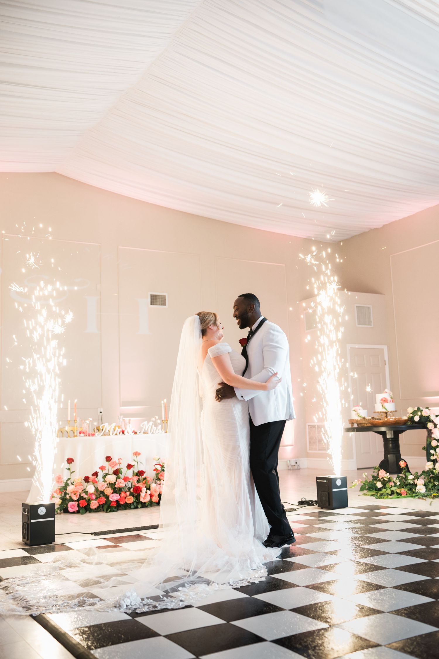 A romantic first dance moment with sparkler effects on a black and white checkered floor.