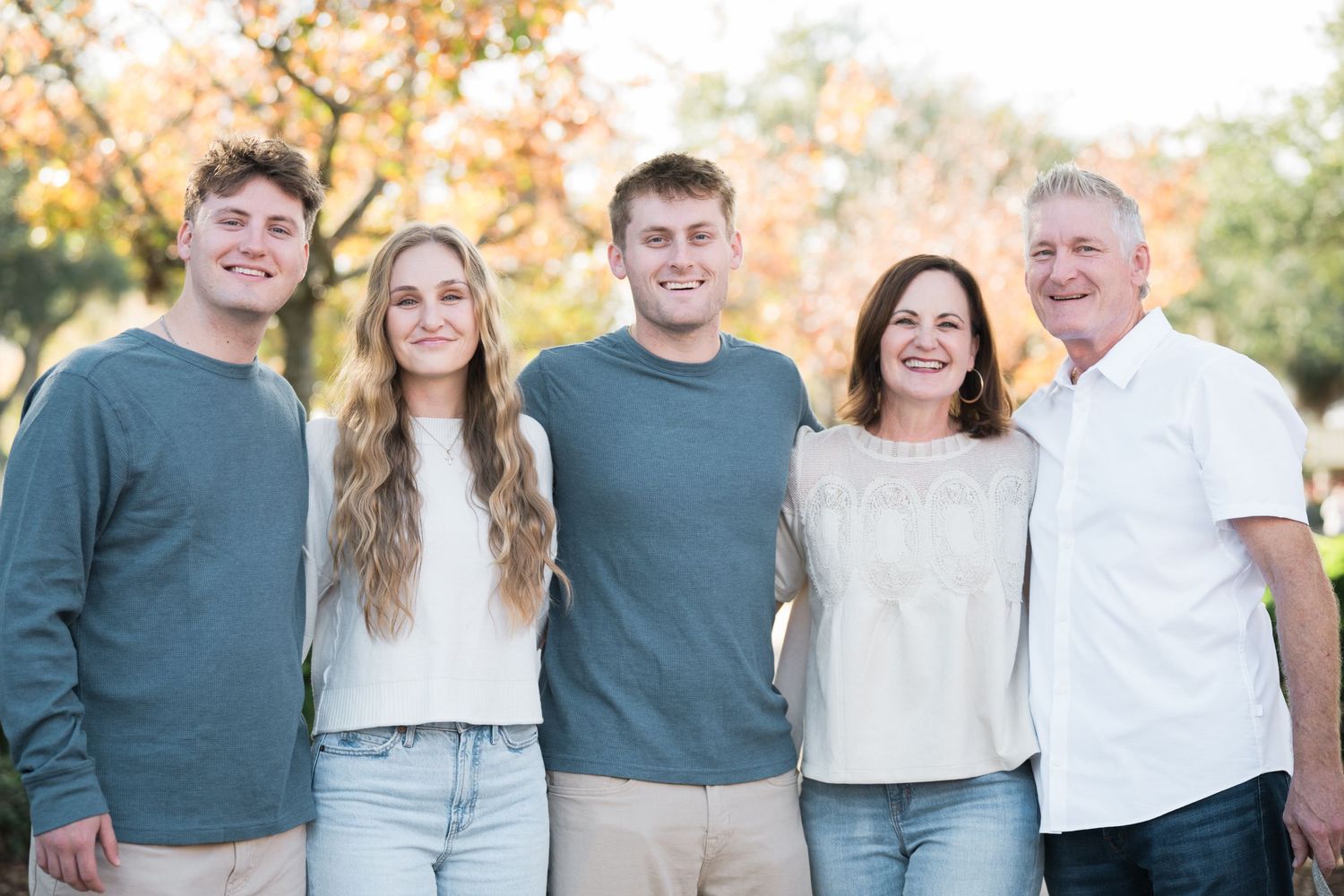 Family members in coordinated blue and white outfits pose together for outdoor portraits.