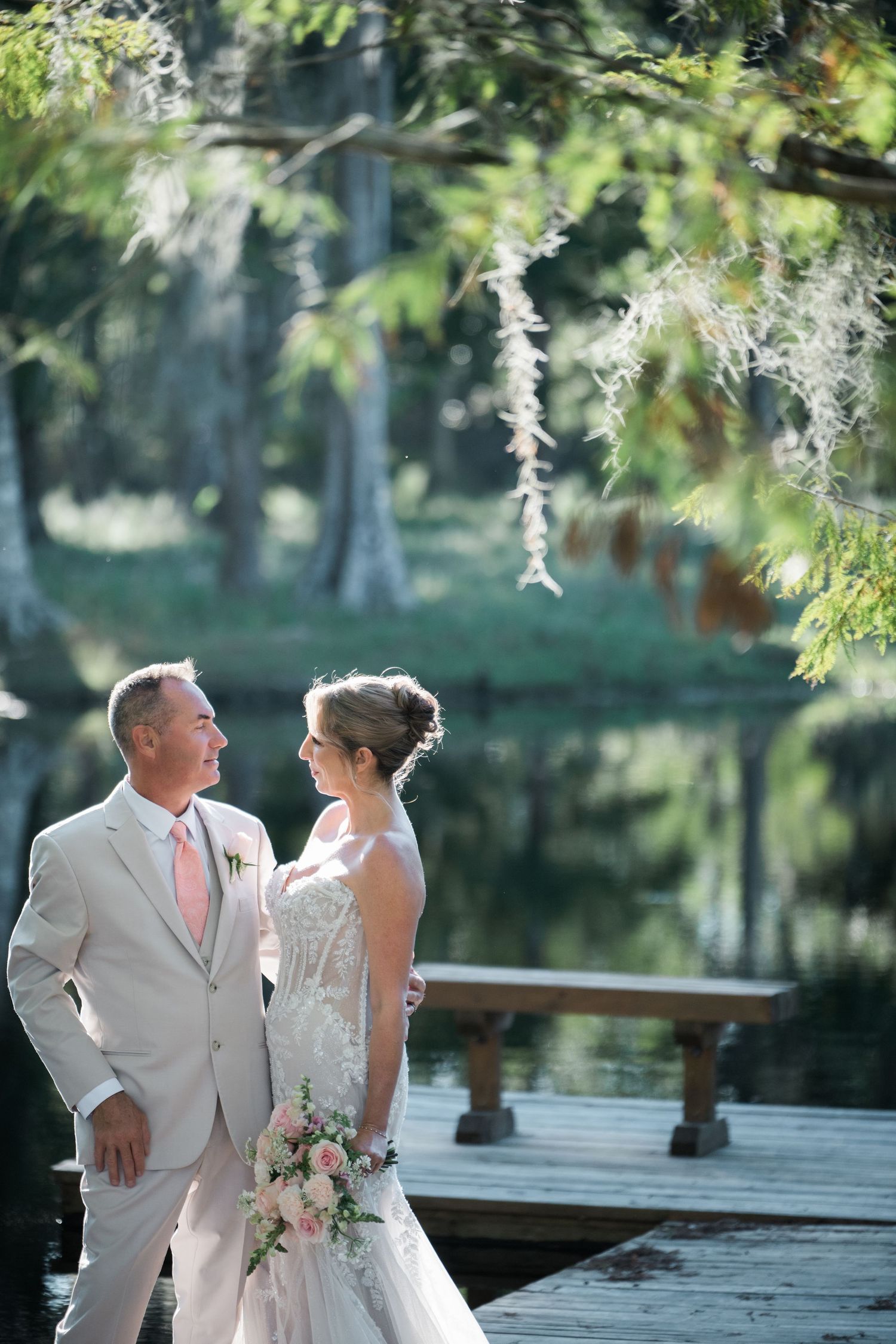 Romantic wedding portraits on an outdoor deck with natural greenery overhead.