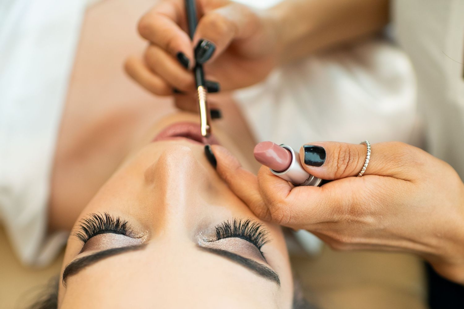 Close-up of makeup application with mascara being applied to long false eyelashes.