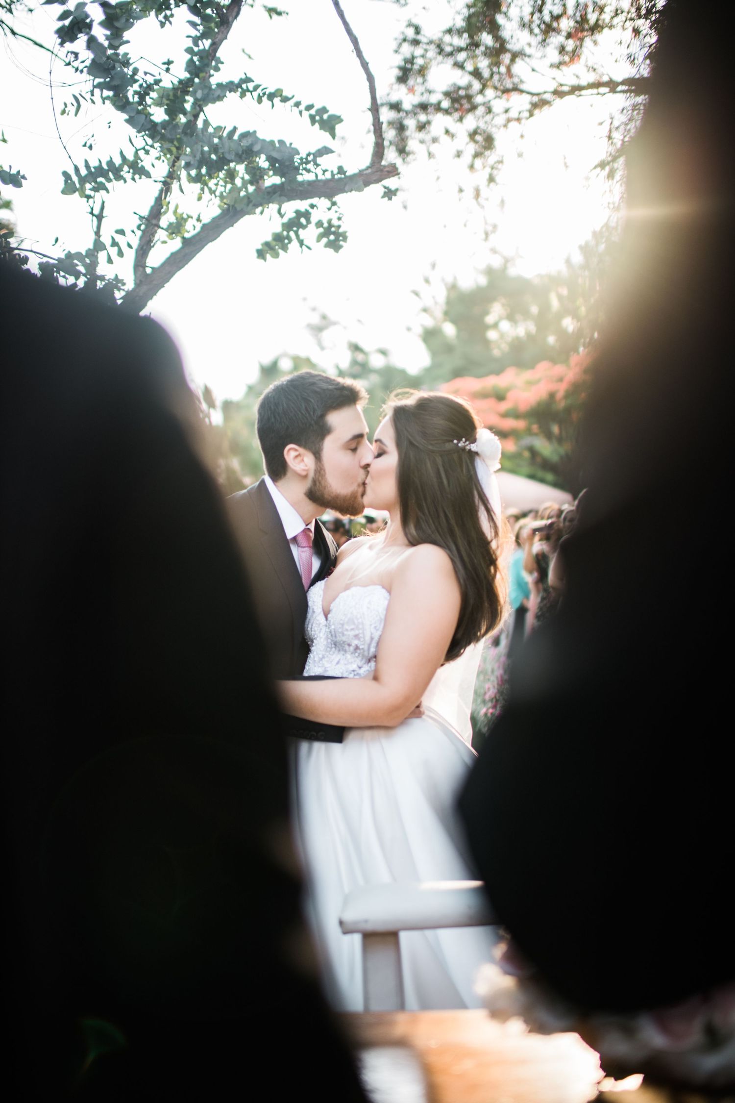 Romantic wedding moment captured through natural sunlight and foliage.