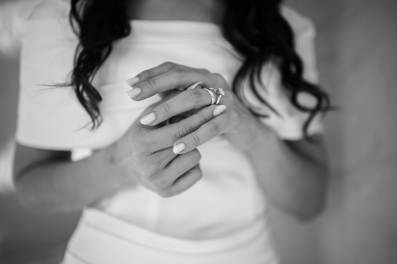 Close-up black and white shot of hands with engagement ring.