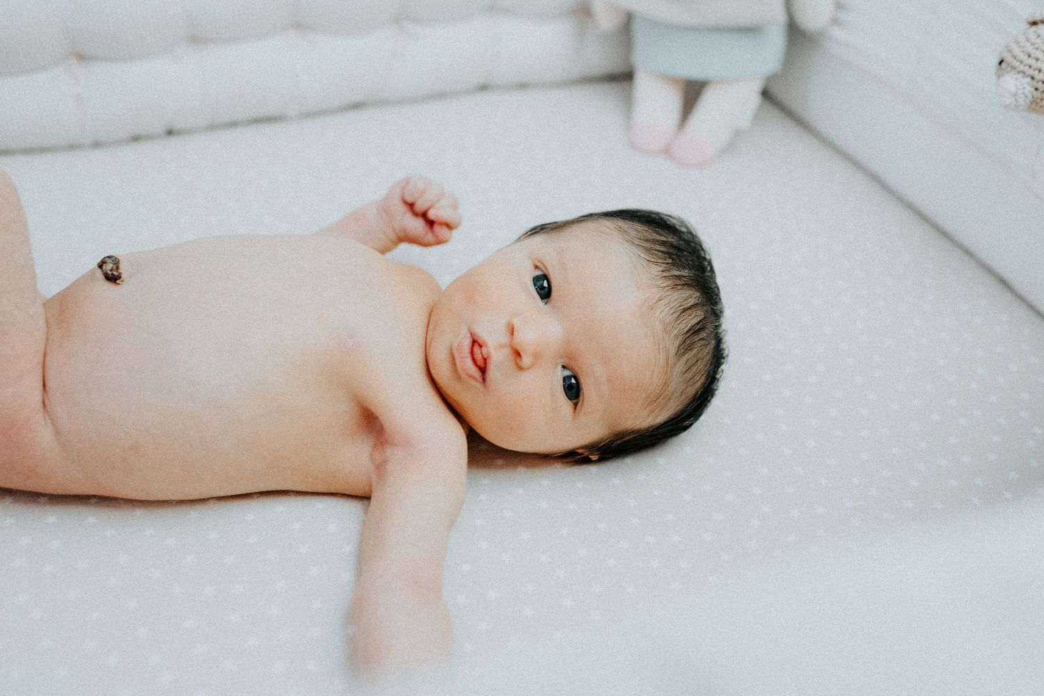 Close-up photos of newborn baby lying on white textured surface.