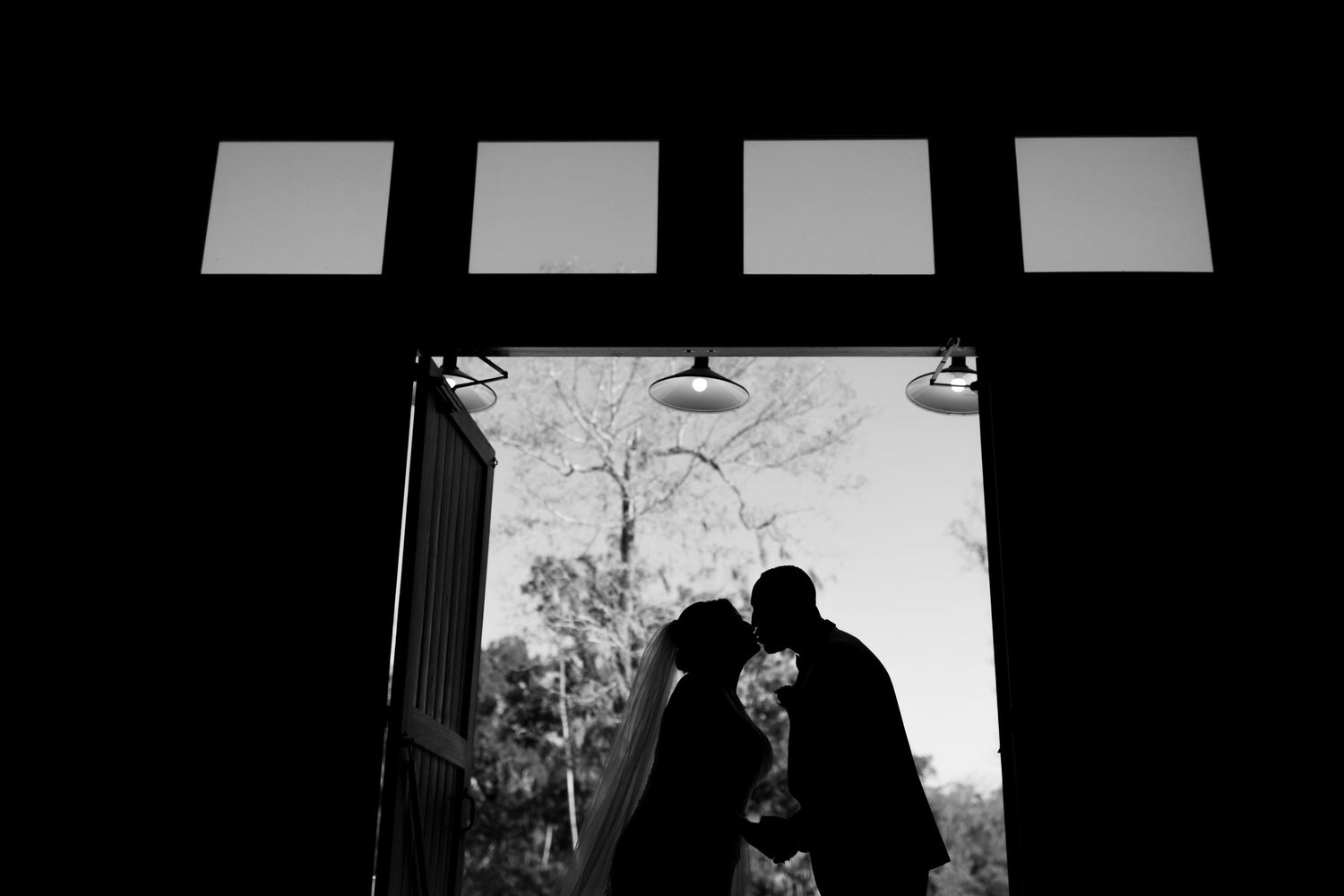 Silhouetted figures against window light in dramatic black and white composition.